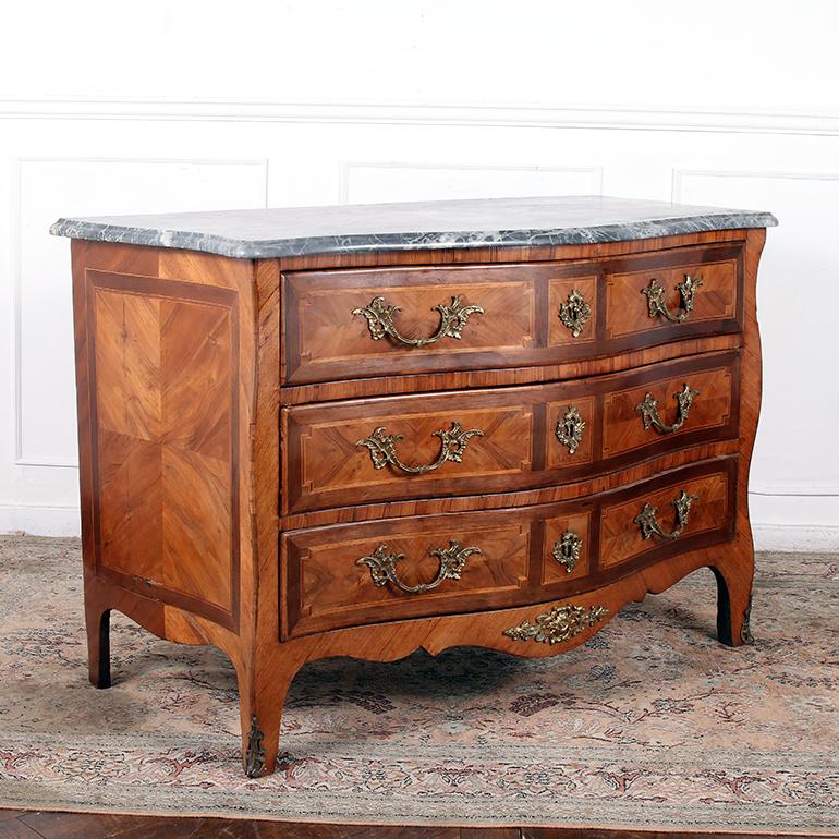 Marble Topped Louis XV Style commode in an impressive parquet design of kingwood, mahogany and rosewood. The serpentine shaped, beveled marble top rests above three bombe front drawers with original gilt bronze handles and escutcheons. The sides