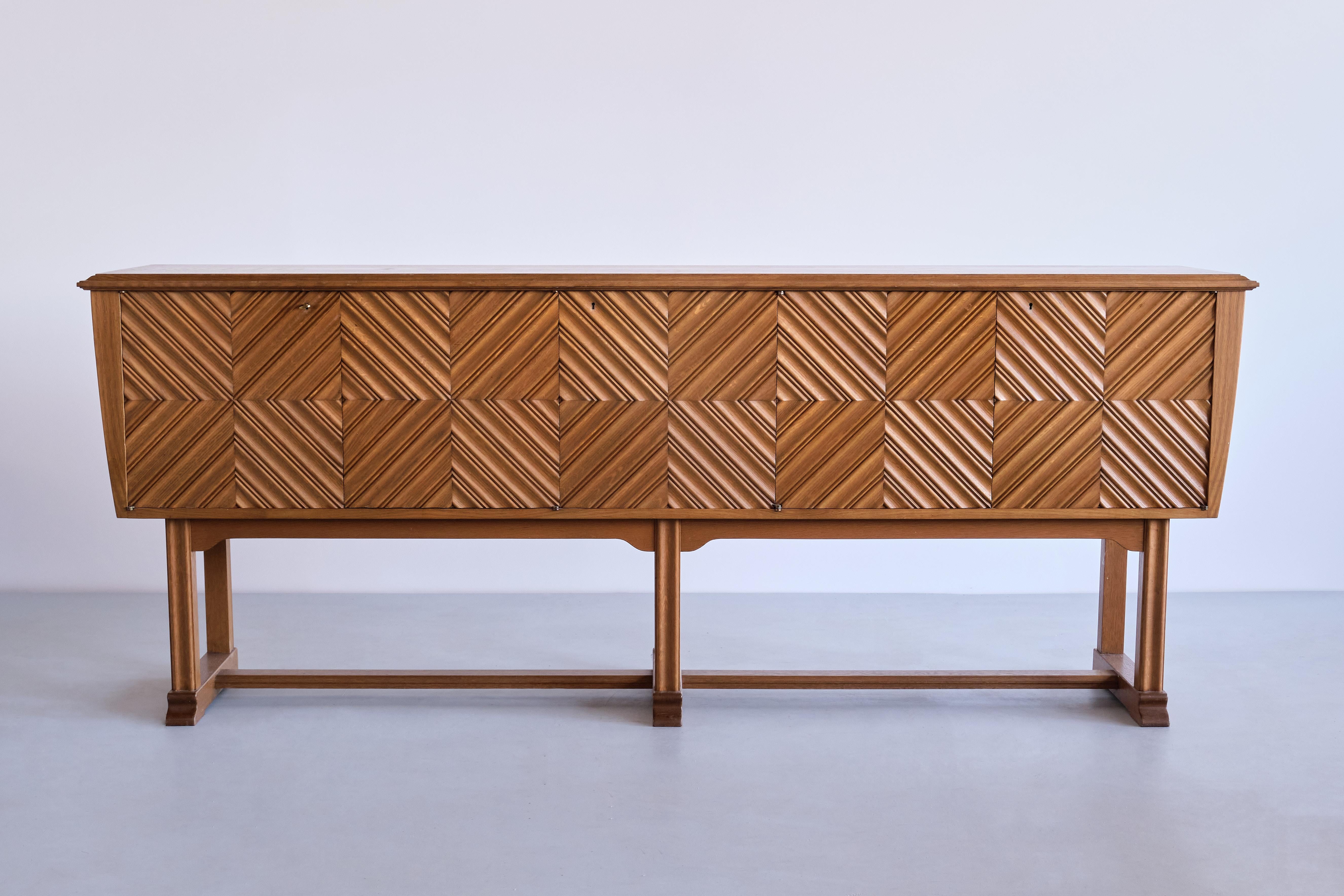 This exceptional sideboard was designed by Ludvig Sturm and produced by Inrednings-Kompaniet AB in Malmö, Sweden in 1948. 

The sideboard is entirely made of solid oak wood. The exterior is composed of five doors, each panelled with four squares of