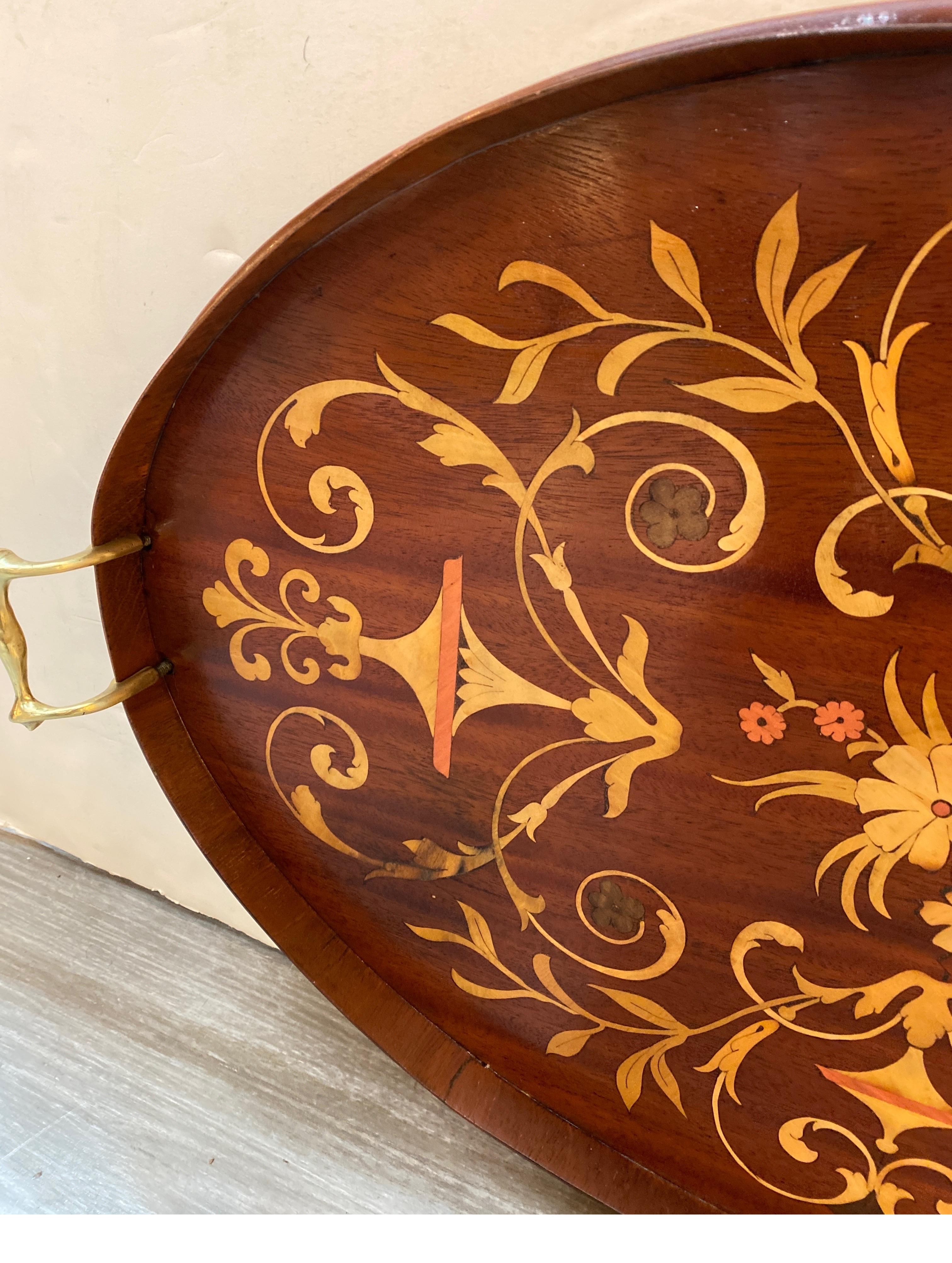 Graceful mahogany tray with brass handles, all over inlay in satinwood and other exotic woods.  The tray measures 26 inches wide handle to handle, 16 inches deep.  The finish is smooth with slight aged dark area near outer edge. 