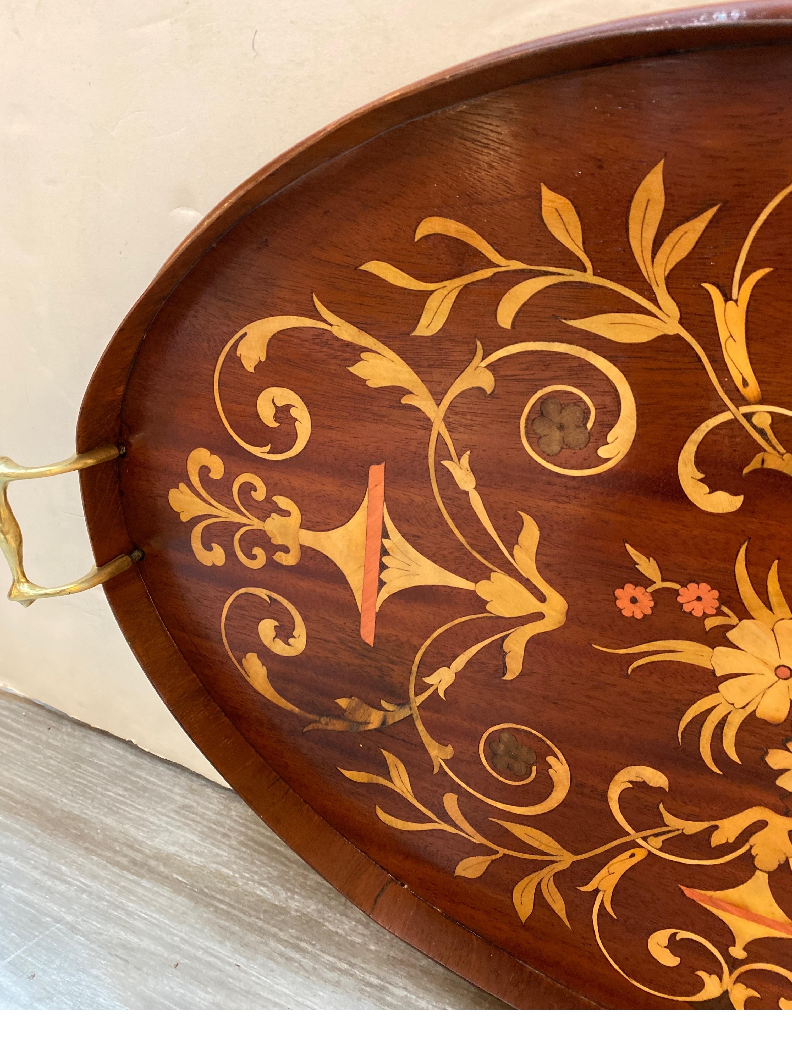 Elegante bandeja de caoba con asas de latón, incrustaciones de madera satinada y otras maderas exóticas.  La bandeja mide 26 pulgadas de ancho de asa a asa y 16 pulgadas de profundidad.  El acabado es liso, con una ligera zona oscura envejecida