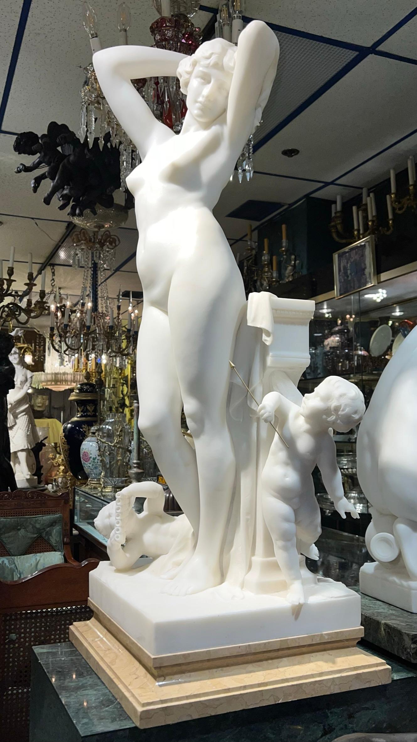 Important white marble sculpture by the Italian-born master, Luca Madrassi (1848-1919), depicting a standing nude beauty surrounded by three cherubs, two playing bronze flutes and one with bronze arrow in hand, and mounted on a stepped,