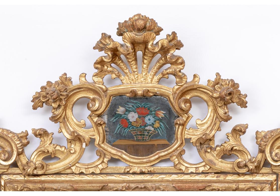 Avec un cadre général en forme de volutes de feuillage. Le cimier en forme d'éventail ouvert sur un panneau de cartouche en miroir peint avec un panier de fleurs colorées rappelant le type de sujet vu dans la peinture au pochoir Theorem. L'entourage