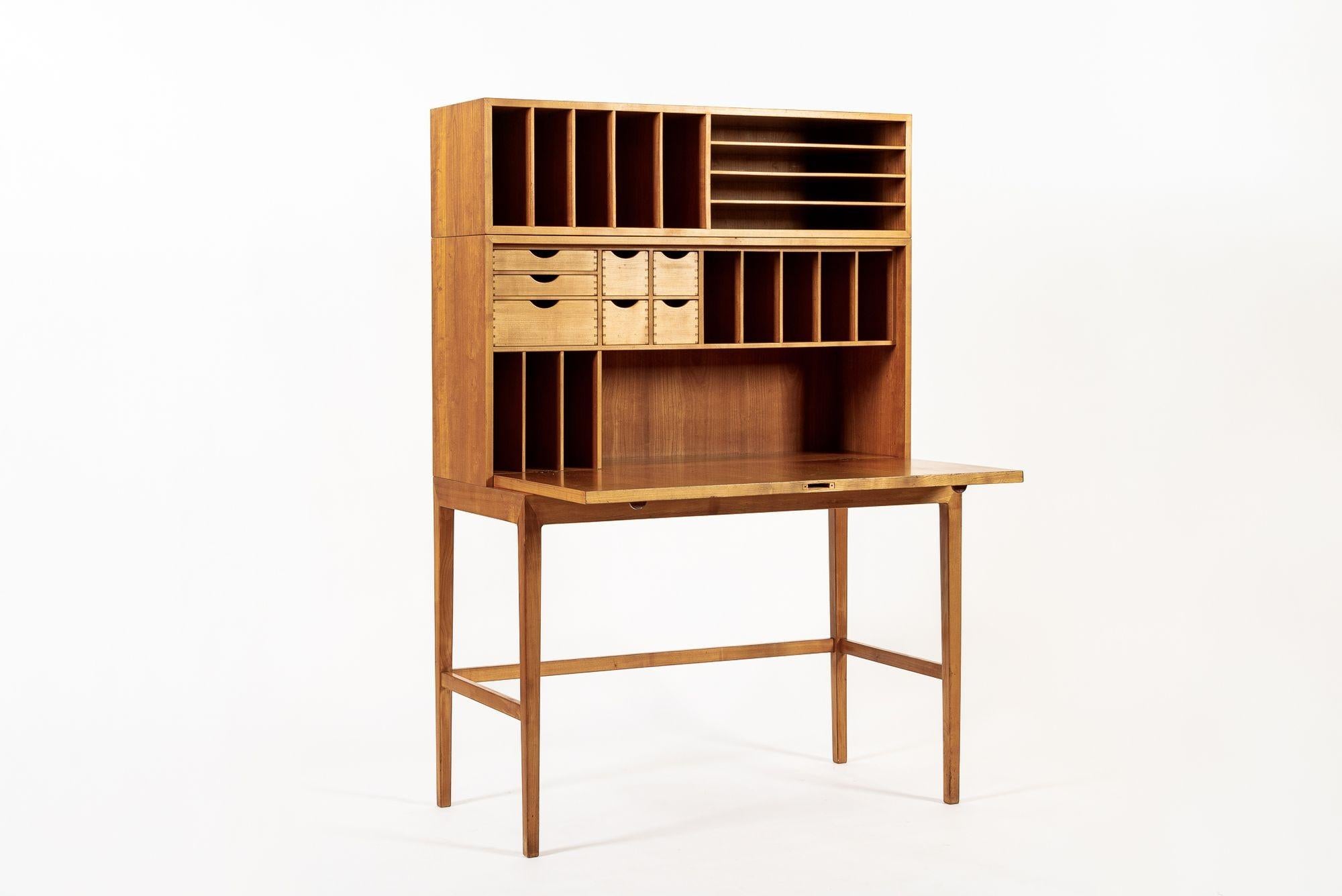 This exceptional vintage mid century Danish modern cherry wood secretary desk with wall shelf designed by Nanna & Jørgen Ditzel was made in Denmark circa 1950. The cabinet is impeccably crafted from cherry wood with a warm honey tone and beautiful