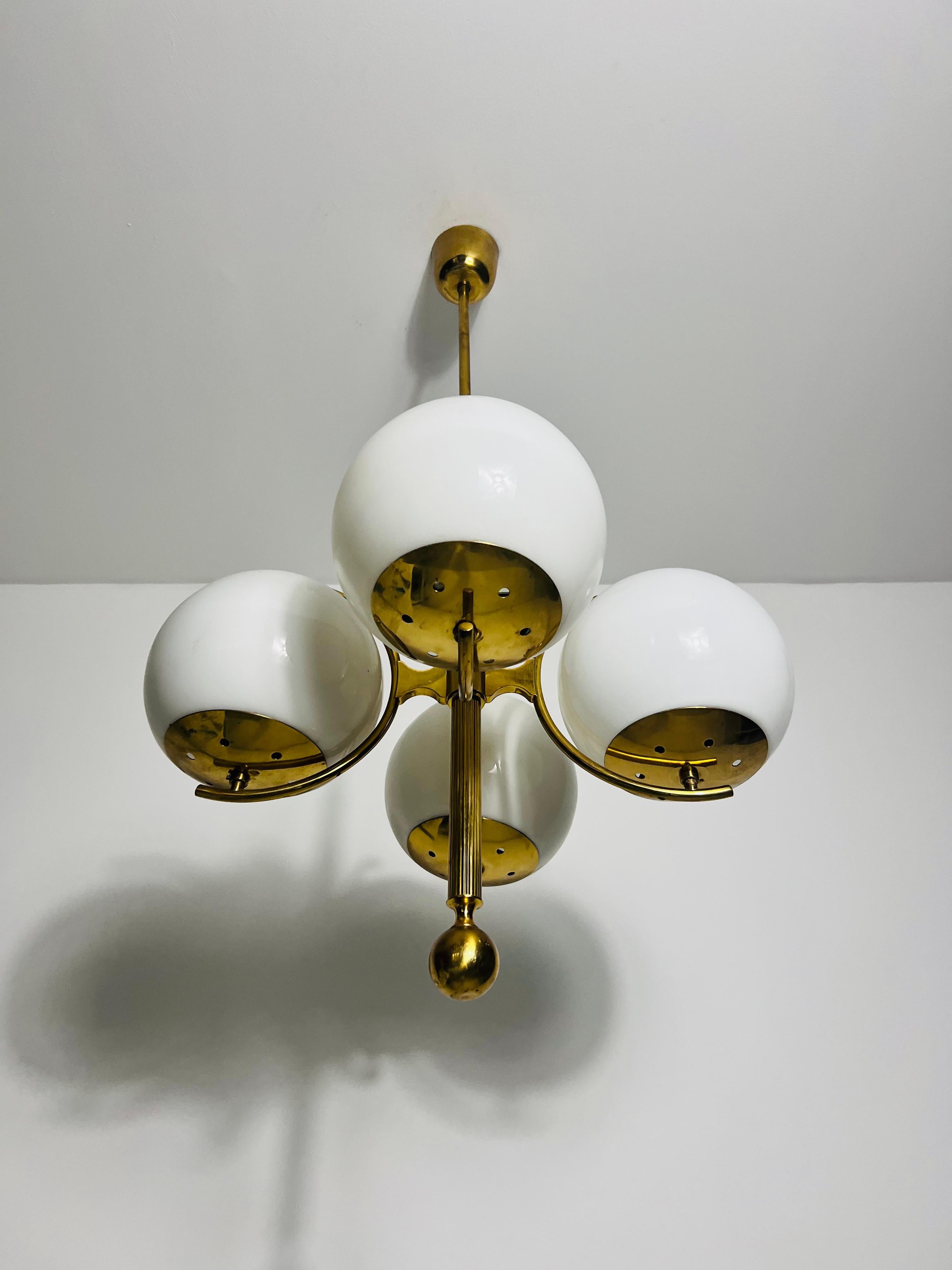 Ce lustre du milieu du siècle de Kaiser Leuchten, fabriqué en Allemagne dans les années 1960, présente un design captivant de l'âge de l'espace. Son esthétique épurée et futuriste est soulignée par quatre boules de verre opalin joliment arrondies