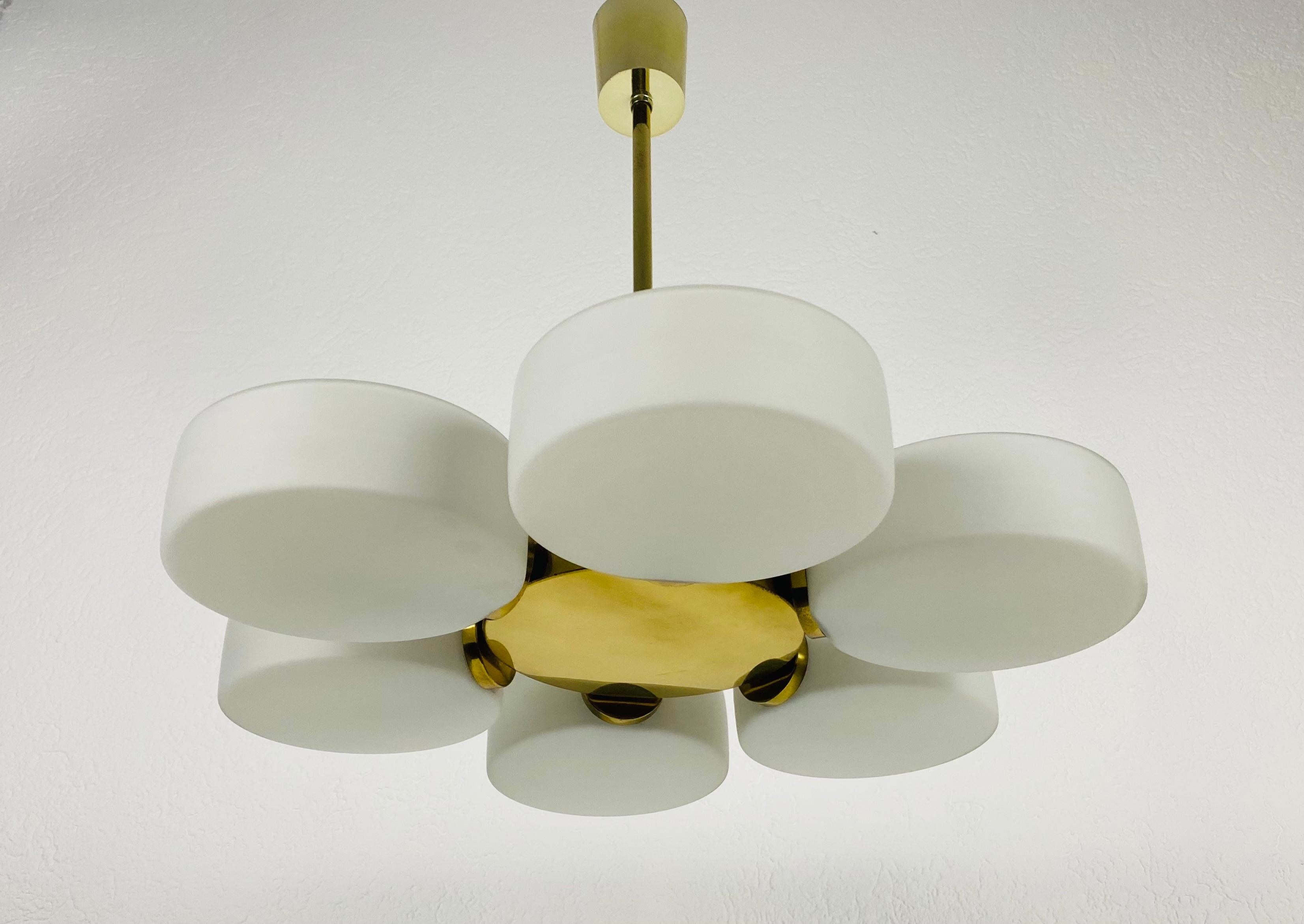A midcentury chandelier by Kaiser Leuchten made in Germany in the 1960s. It is fascinating with its Space Age design and six opaline glass balls. The circular body of the light is made of polished brass, including the arms. 

Good vintage
