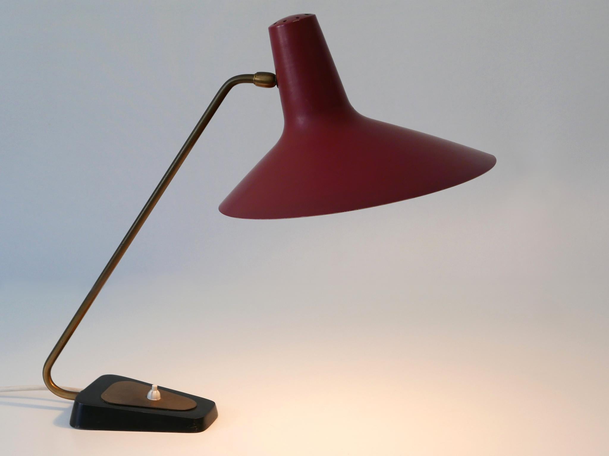 Extremely rare, elegant and adjustable Mid-Century Modern table lamp or desk light. The large lamp shade adjustable in various postion . Manufactured by Gebrüder Cosack, Neheim-Hüsten, Germany, 1950s.

Executed in Bordeaux color enameled