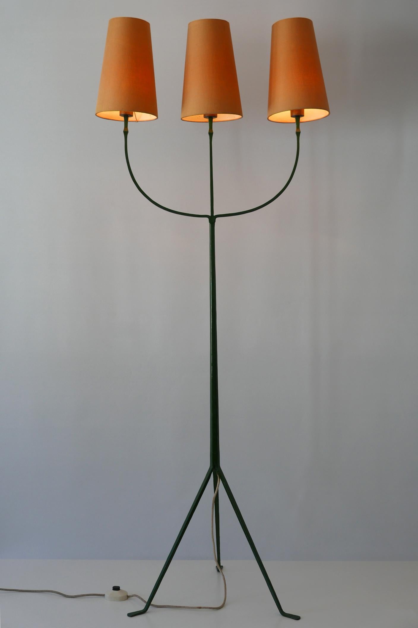 Exceptional and elegant three-flamed Mid-Century Modern floor lamp. Manufactured probably in France, 1950s.

Executed in dark green enameled wrought iron and brass, the lamp needs 3 x E27 / E 26 Edison screw fit bulbs, is wired, and in working