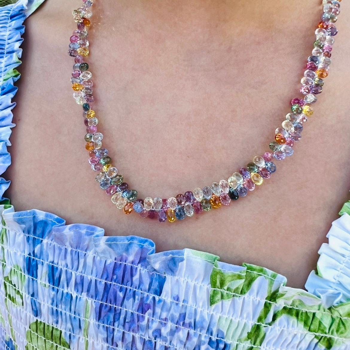 Candy-colored and fanciful, this 18k gold necklace is a stunner! The multi-colored briolette-cut sapphires total approximately 140.0 carats, and finished with a ball form clasp shining with round brilliant-cut diamonds. It weighs 33.9 grams and