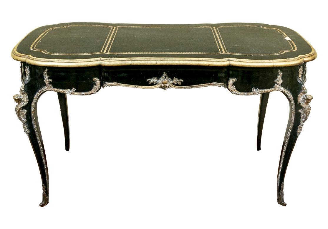 A fine Antique French Bronze mounted writing table with particularly fine form dating to the late 19th Century. The table features all over Bronze mounts including Caryatid figures on the Cabriolet legs, Foliate mounts outlining the desk at apron