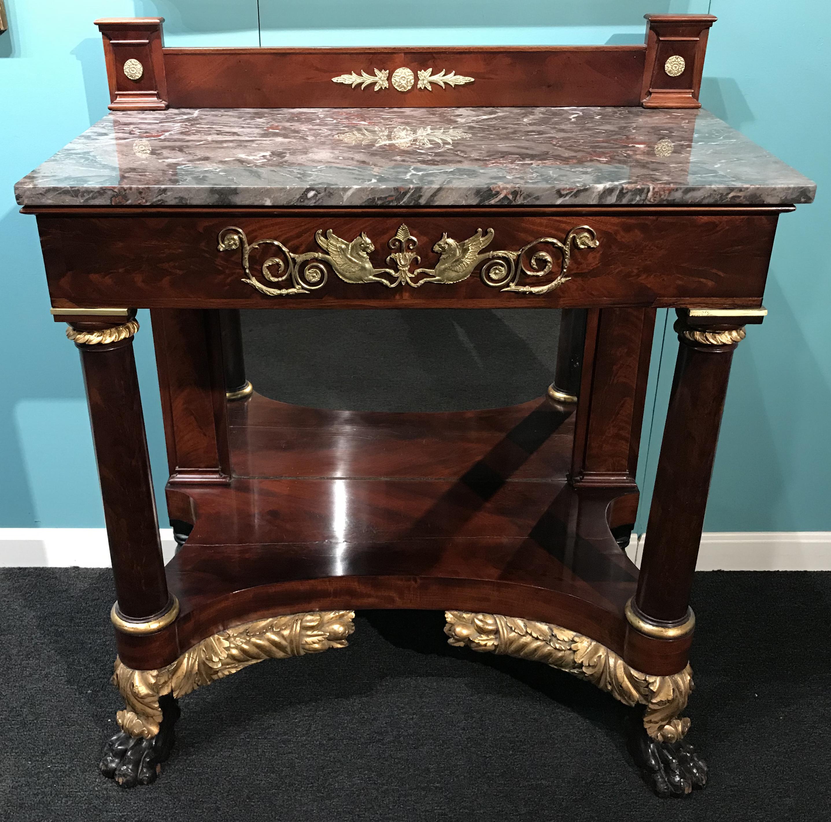 An exceptional Federal period mahogany pier table, console or server with rectangle marble top accented with a mahogany raised backsplash with applied ormolu rosettes and foliate decoration, surmounting a front apron with front applied griffin