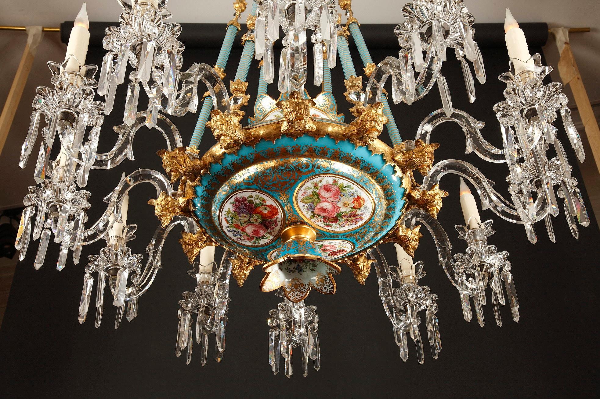 Rare Baccarat opal glass chandelier composed of a cup suspended by six opal glass and gilded bronze articulated chains from which go twelve cut-crystal light-arms and of a ceiling lamp with cut edge. Rich decoration of a “bleu celeste” opal-glass