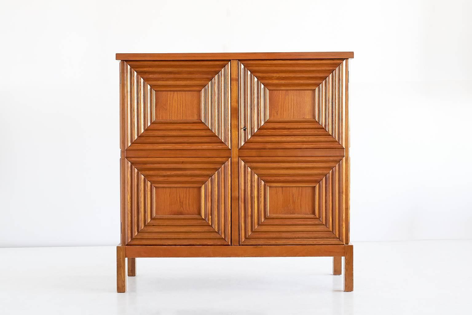 This cabinet designed by Oscar Nilsson and executed by the master cabinetmaker Jacob Wickman was produced in Sweden in the early 1940s. The exterior of the oak cabinet is composed of eight geometrically profiled frames, four on the front and two