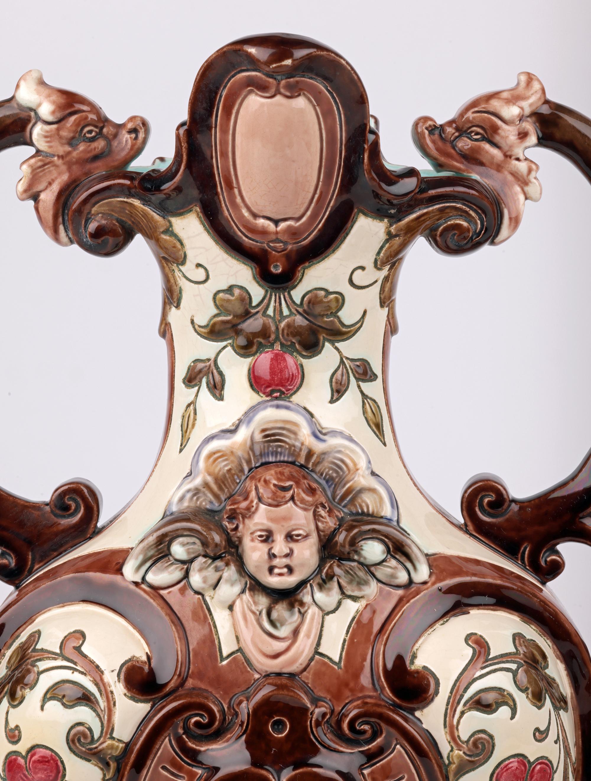 A exceptional, large and impressive pair antique twin handled majolica vases originating from one of the top Austrian or Bohemian makers and dating from the 19th century. Possibly exhibition pieces the earthenware vases stand raised on an