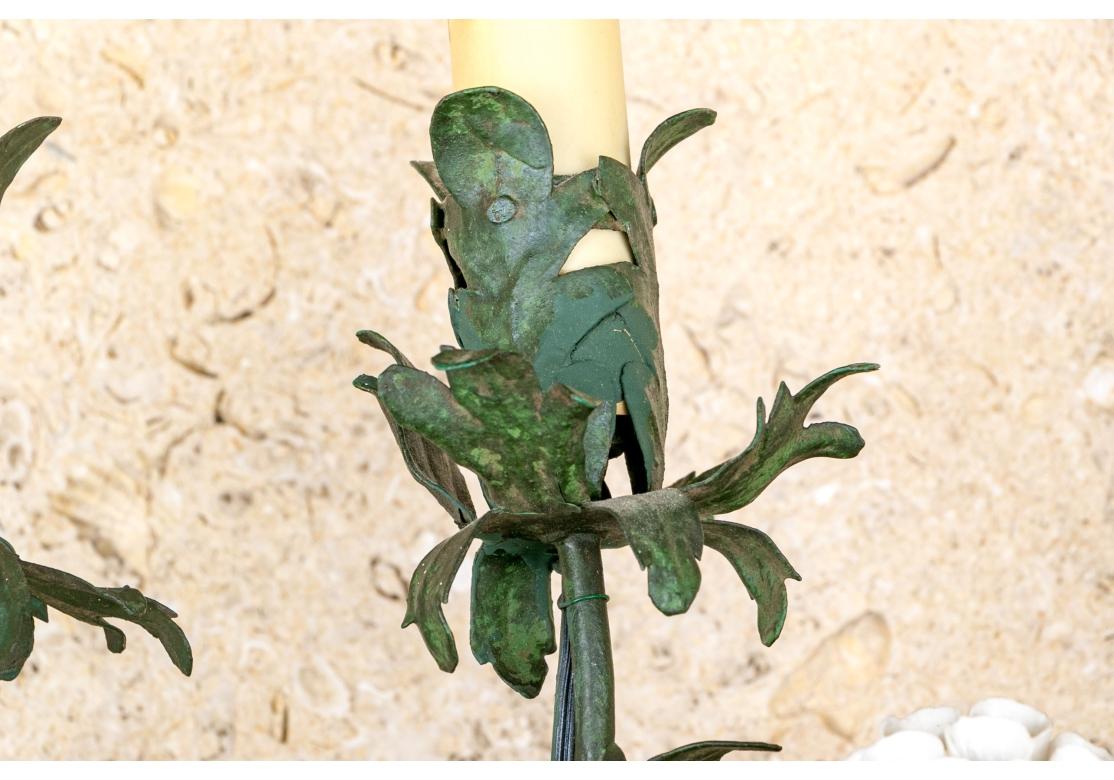 Fina y decorativa pareja de apliques de mediados del siglo XX con flores de porcelana blanca. Probablemente italiano. El metal pintado de verde sostiene dos brazos de candelabro y está adornado con hermosas flores de porcelana de diferentes diseños.