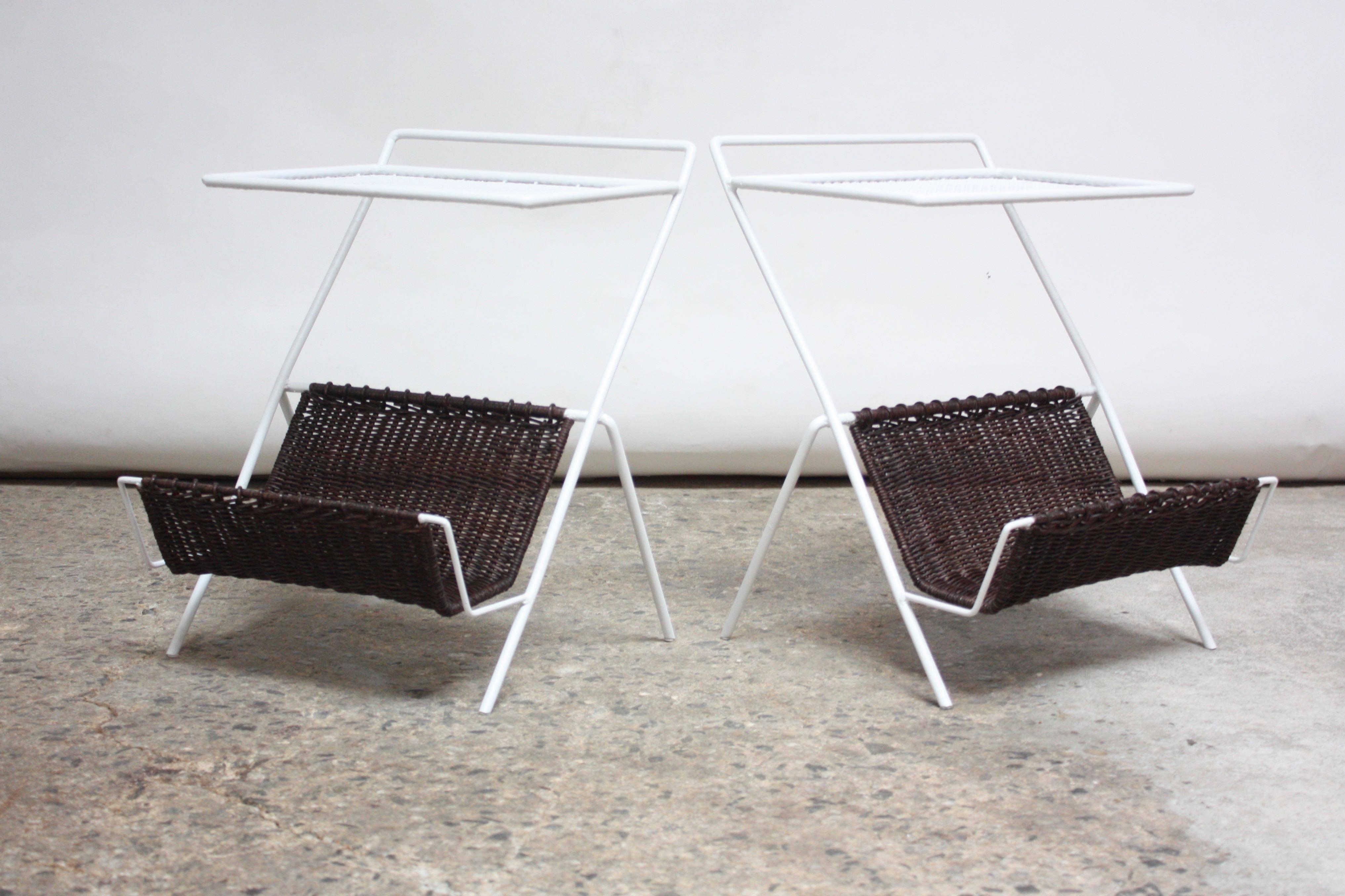 This rare matching pair of rattan and wrought iron tables were designed by Mathieu Matégot (Ateliers Matégot), circa 1950. 
Composed of a perforated surface above a stained rattan rack for books/magazines.
Beautiful, restored condition (originally,