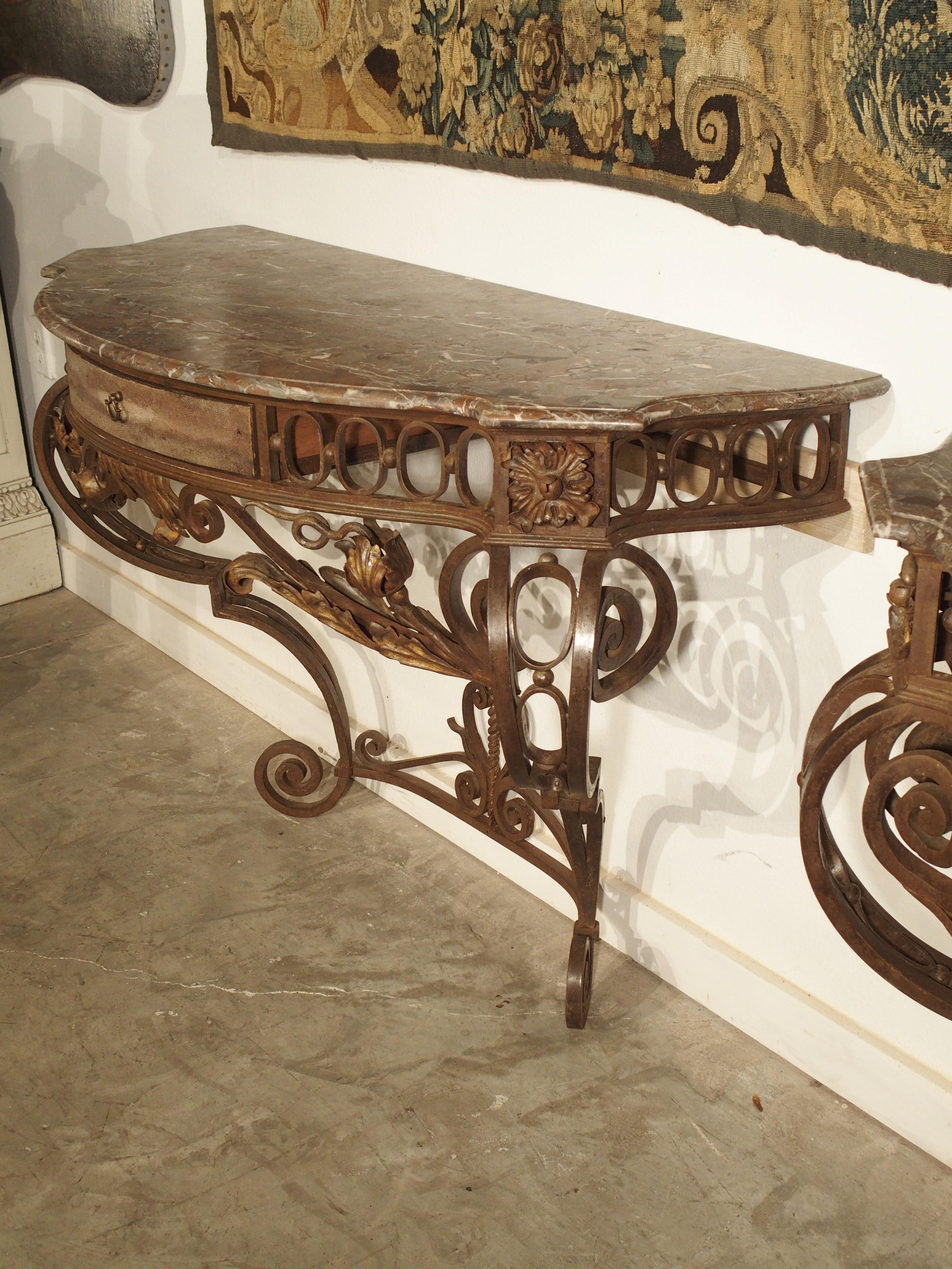 From France, circa 1880, this rare pair of wrought iron consoles have marble tops and shagreen covered wooden drawers.

The marble tops are original to the consoles and feature a “bec de corbin” molded edge. The marble is a Belgian “Rouge Royal”;
