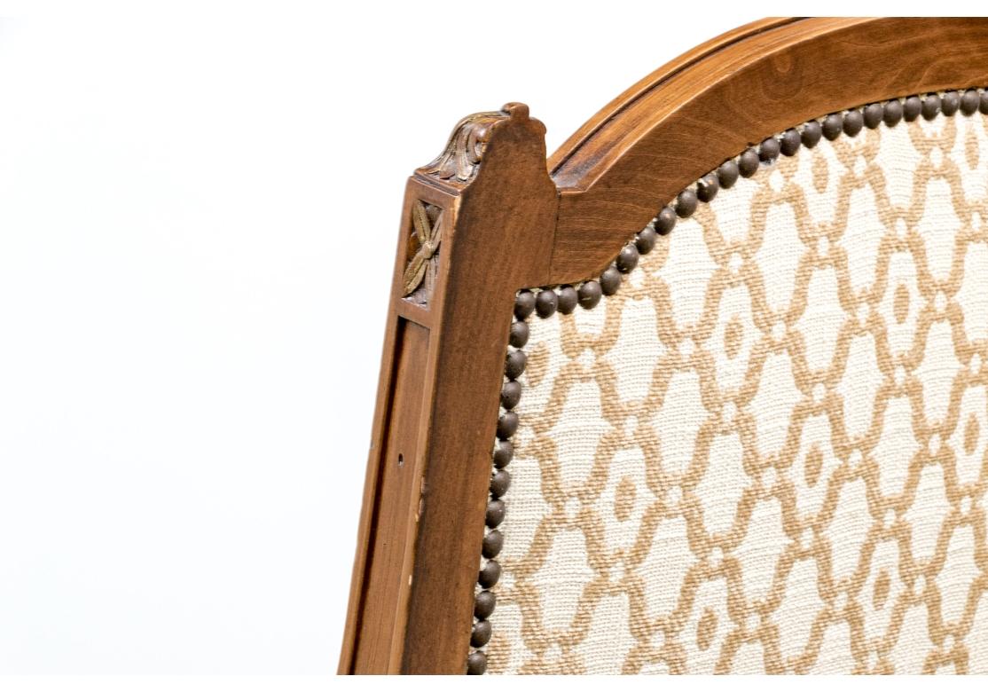 Une paire de Bergeres très confortables, solides et moelleuses, avec des cadres sculptés de feuilles d'acanthe, de rinceaux et de fleurs en forme de cloche, et de fins pieds cannelés et effilés. Les manchettes d'accoudoir et le cadre sont ornés d'un