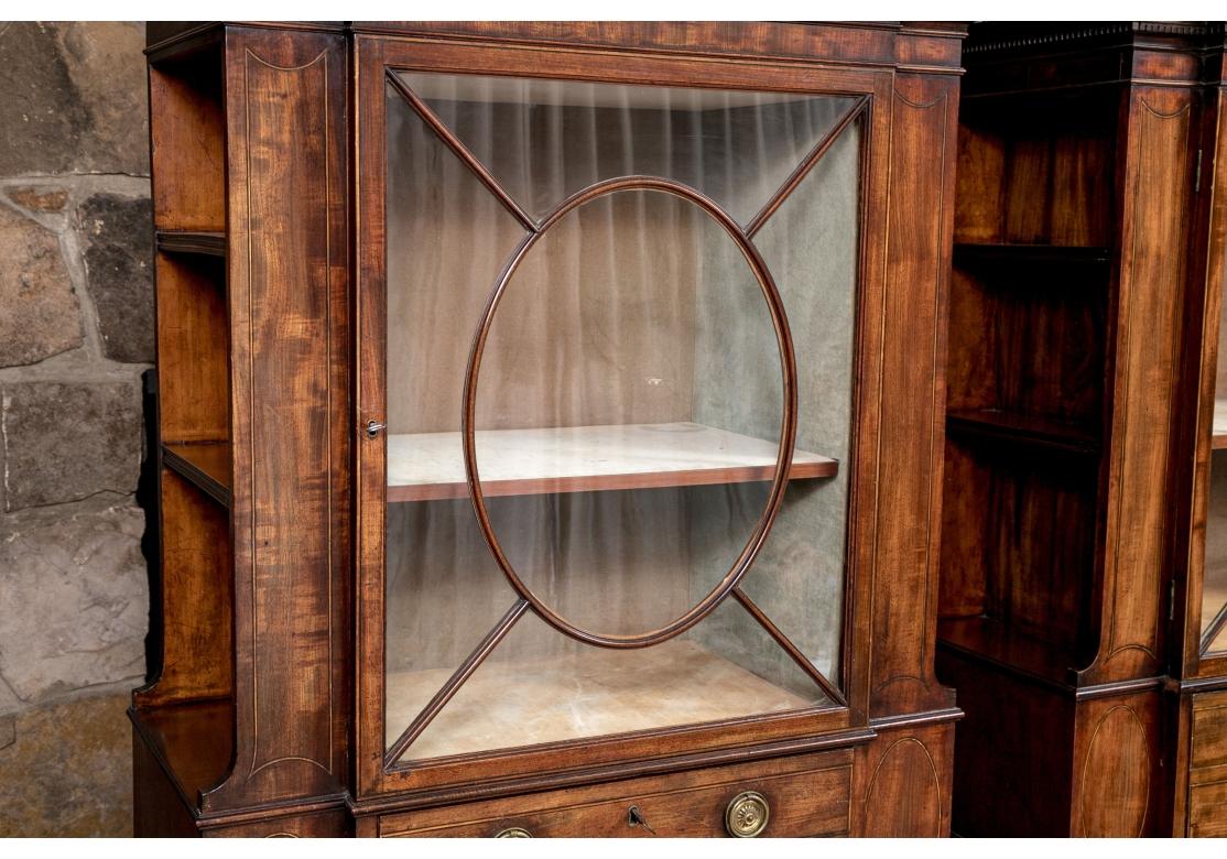 A superb Pair of Secretary Bookcases  having side shelving, inlaid doors, pull-out desk, drawers, ring pulls, handsome geometric glass doors and embossed green leather writing surface . One has a Keyed drawer while the other has drop down desk, and