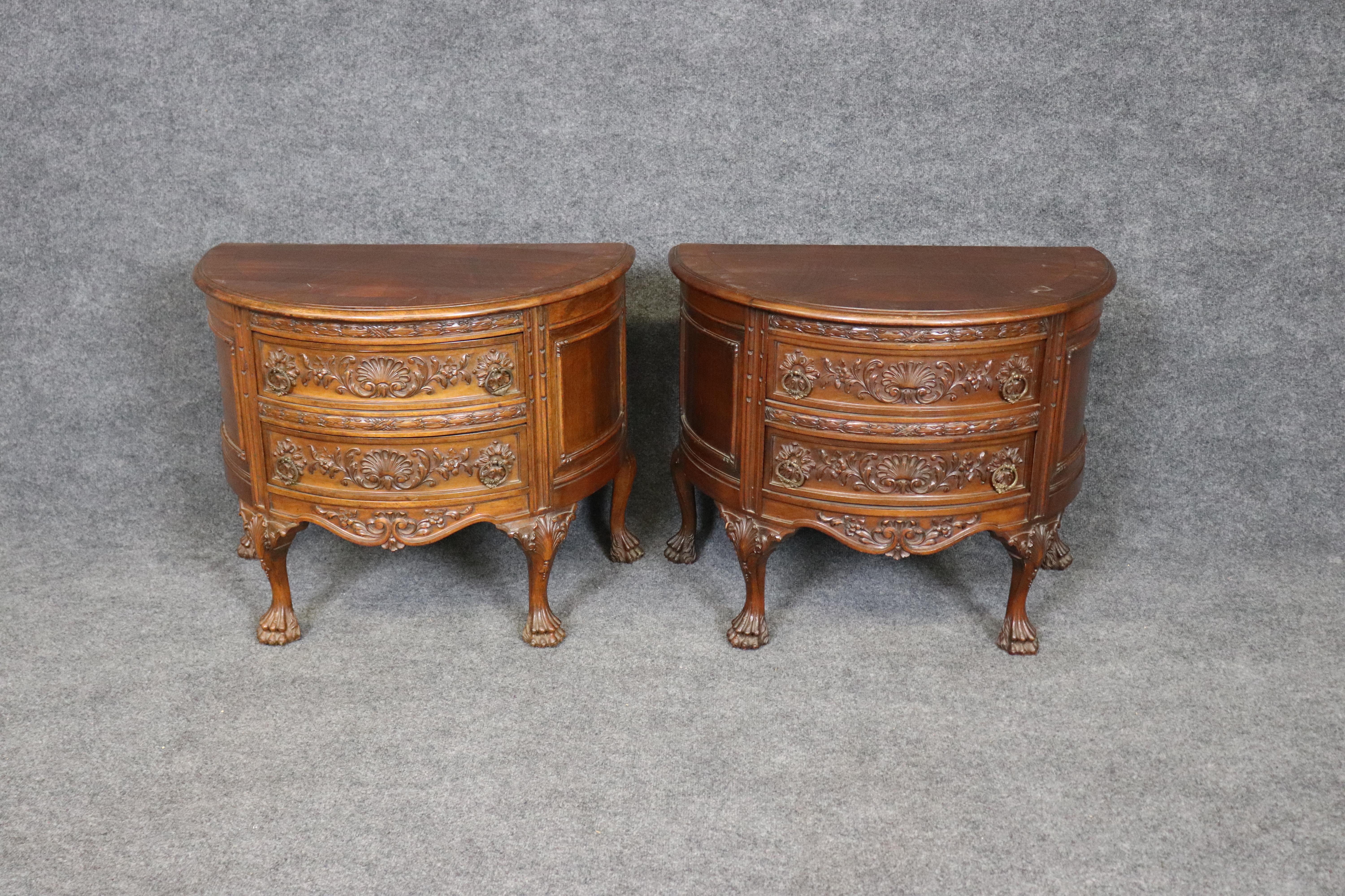 Questa eccezionale coppia di comodini francesi in stile Luigi XV mette in mostra l'arte e la maestria del design europeo. Ogni comodino a forma di demilune è magistralmente intagliato in noce pregiato, con motivi floreali e conchiglie ornate sui