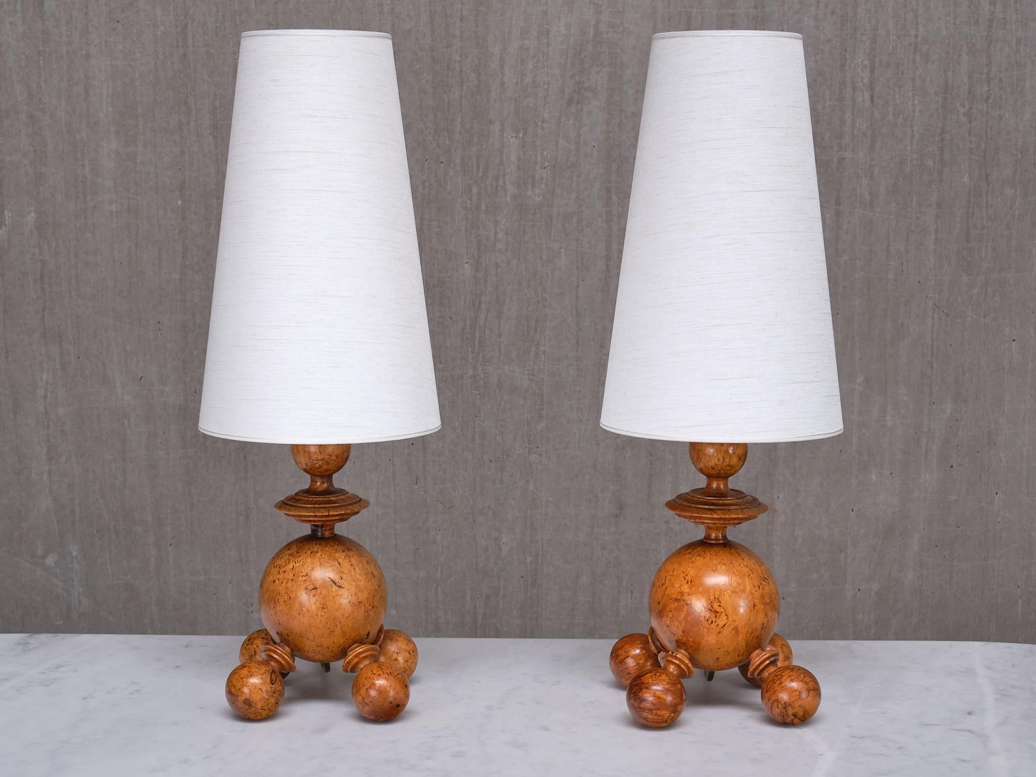 This exceptional pair of table lamps was produced in Sweden in the early 1930s.

The striking design features a large, central orb-shaped body supported by four spherical feet and topped with a finely turned wooden element. Crafted from solid Masur