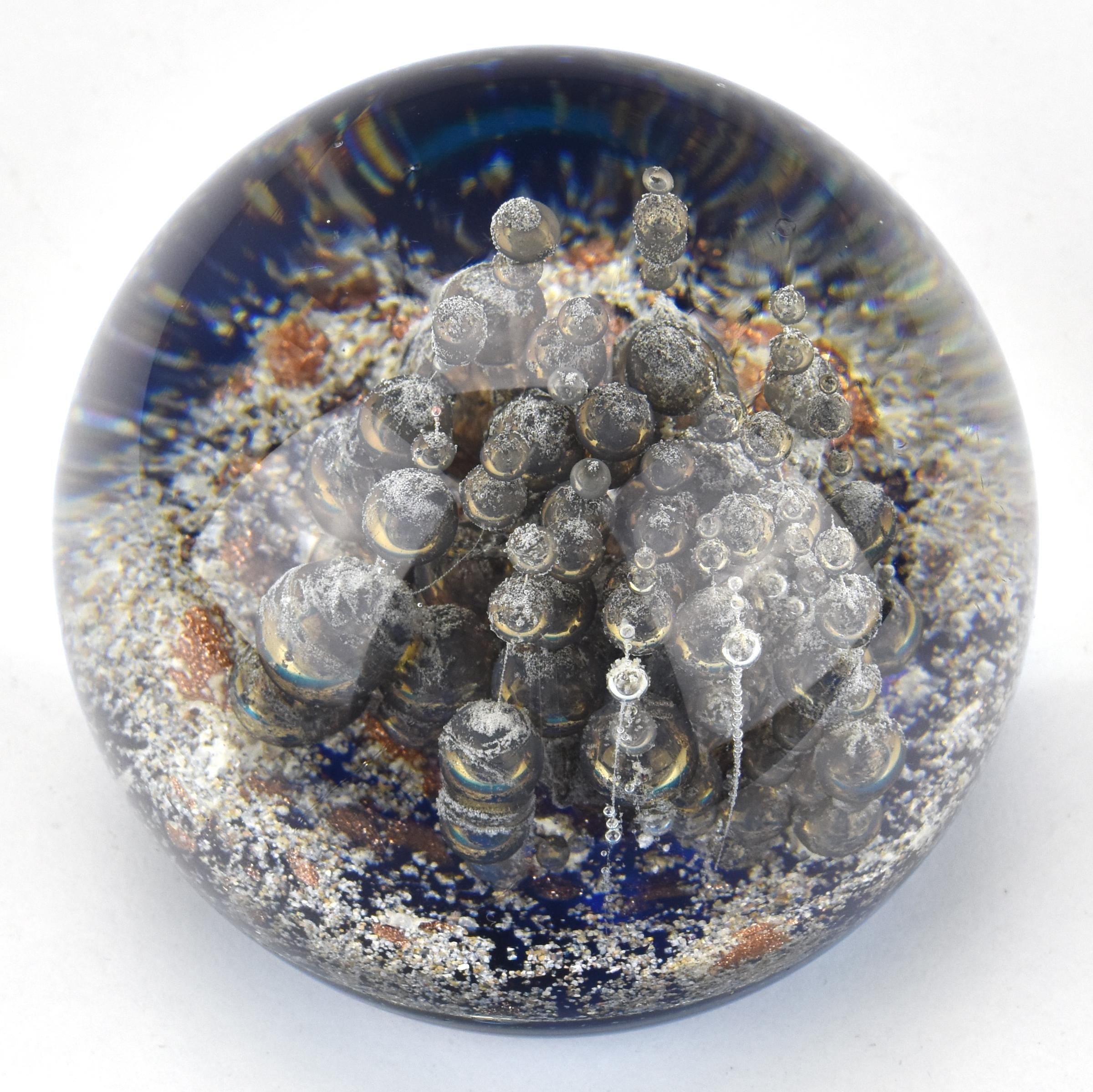 Un superbe presse-papier ou objet en verre d'art moderne du milieu du siècle dernier avec des bulles de style vulcano montantes avec une poussière de métal incluse sur un fond bleu portant une étiquette en papier Murano authentique. 