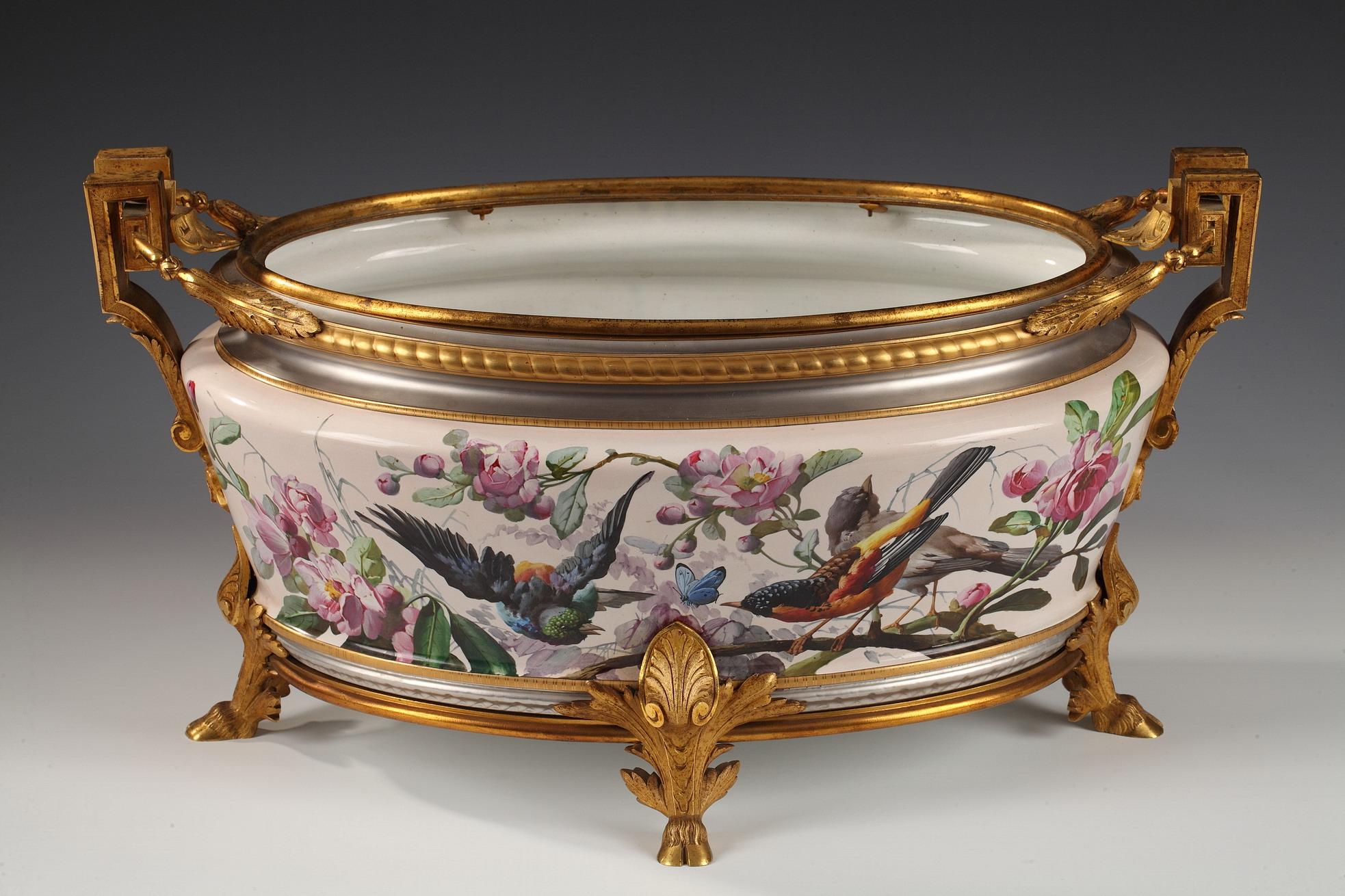Signed ALPH. GIROUX PARIS on the bronze mount ; 
Marked L.M. & Cie and MONTEREAU under the earthenware. 

Planter painted with peonies, birds and butterflies, gilded and platinium filets, inserted in gilt bronze mounts on four foliate and hooves