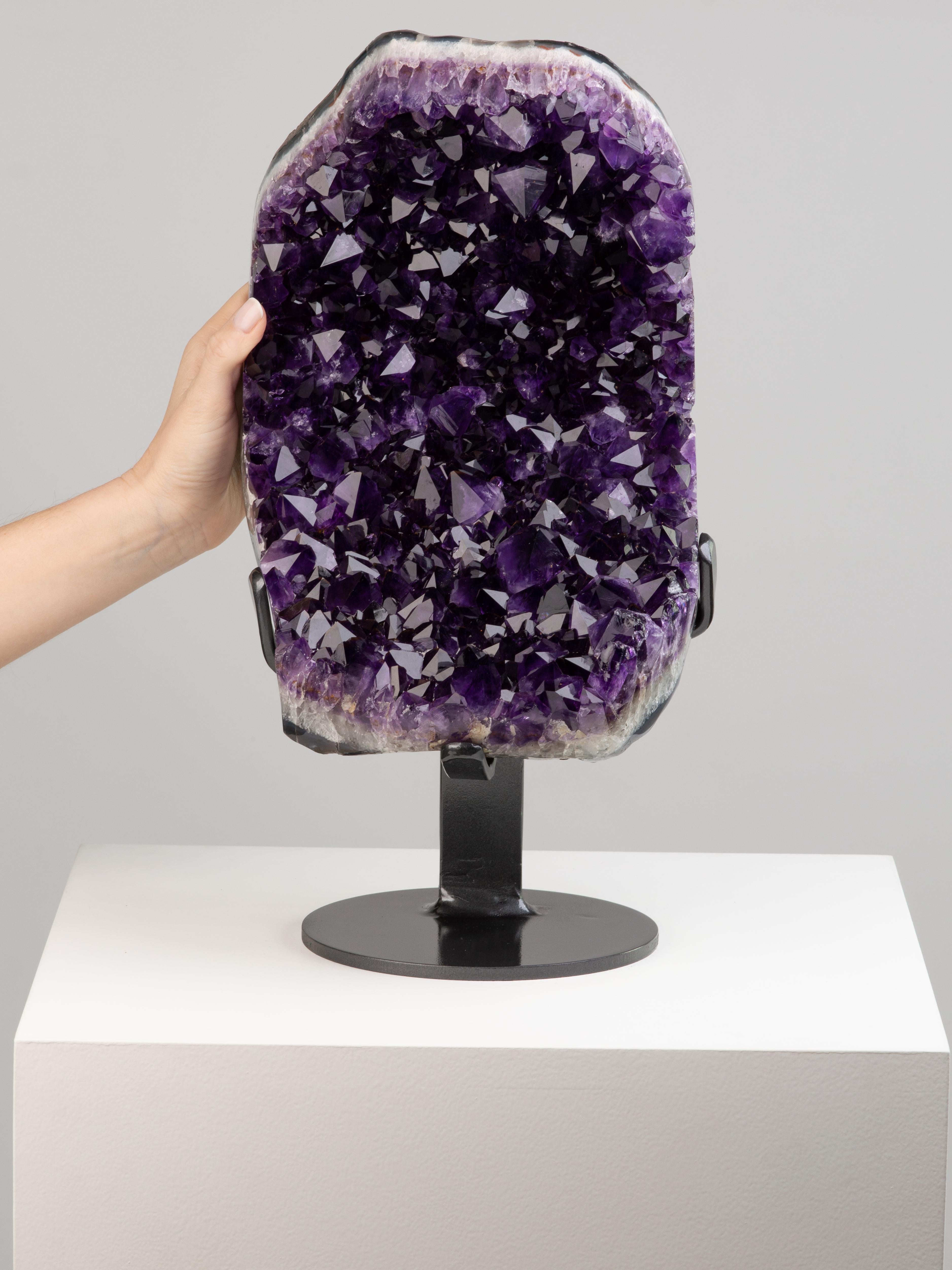 Amethyst of the deepest colour is shown here in a formation resembling
an open mouth. The crystals are of high peaks with red tints toward the
tips. the borders unpolished to reveal the rough quartz and thin exterior
shell.

This piece was