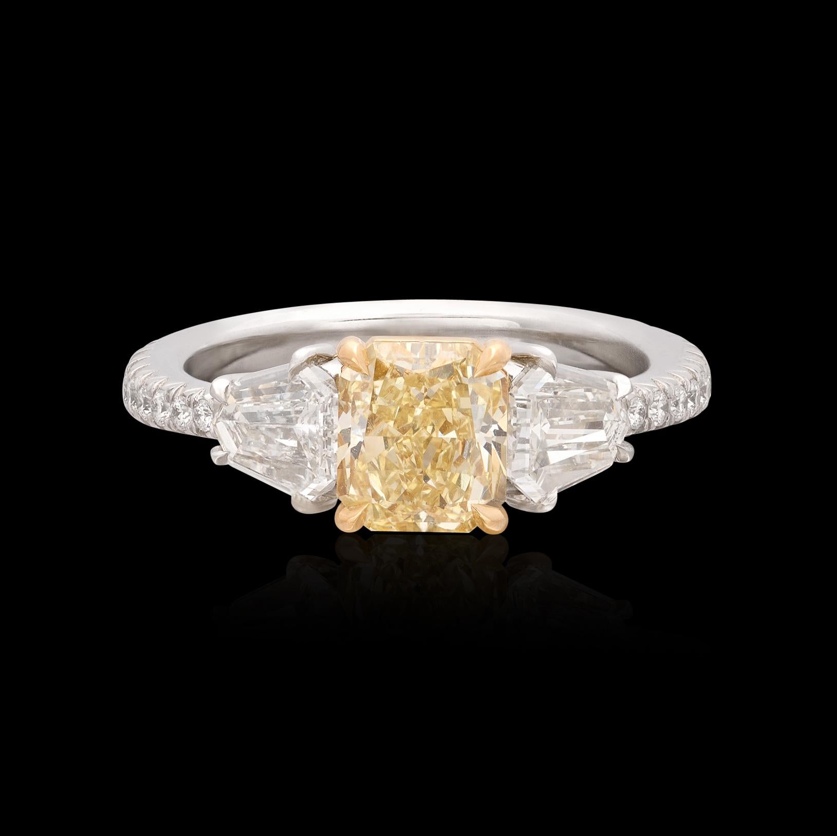A yellow diamond stunner that is sure to turn heads! This extraordinary ring features a 1.38 Radiant Cut natural yellow diamond flanked on either side by a phenomenal white Kite Cut diamond along with 20 fine Round Cut diamonds perfectly set 3/4