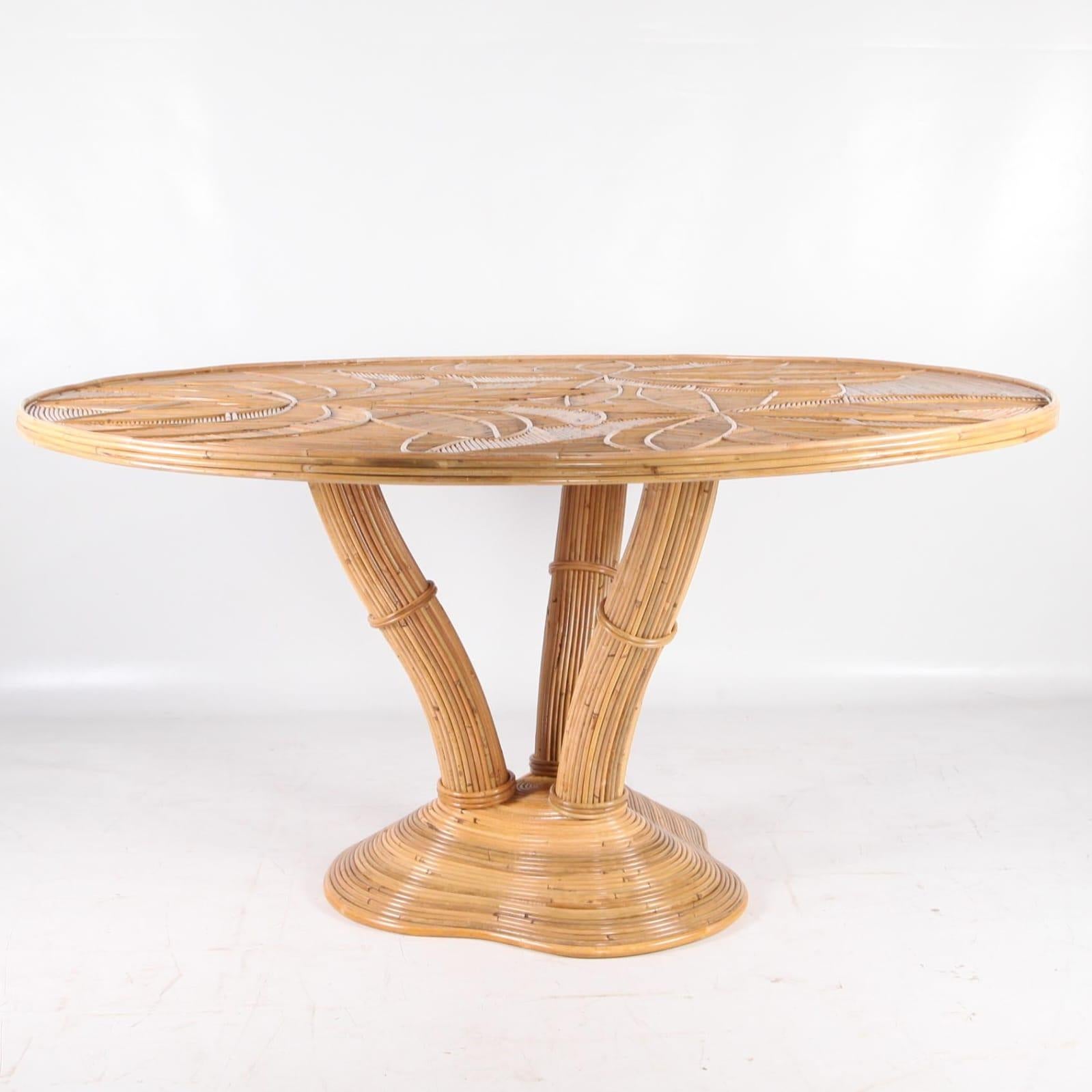 Exceptional round rattan dining table.
Legs representing a palmtree, top with palms patterns covered by a glass top. 
High quality work entirely hand made, rare!
