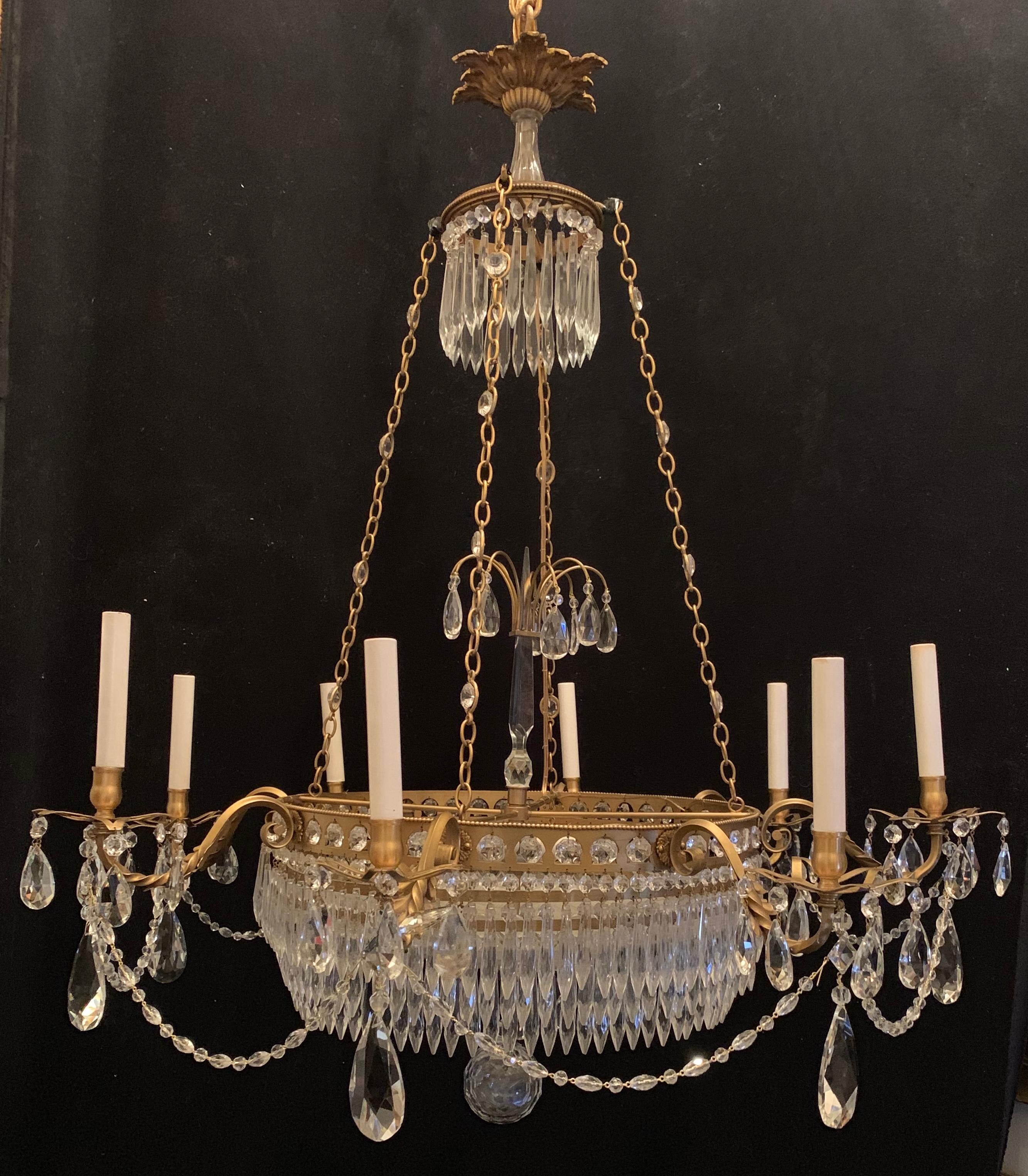 An exceptional French Regency gilt bronze and cut crystal center bowl Empire / Baltic eight-arm chandelier dressed with 3 tiers of crystal drops and crystal swags draping from the bobeches that are mounted to a pierced gallery rim fitted with