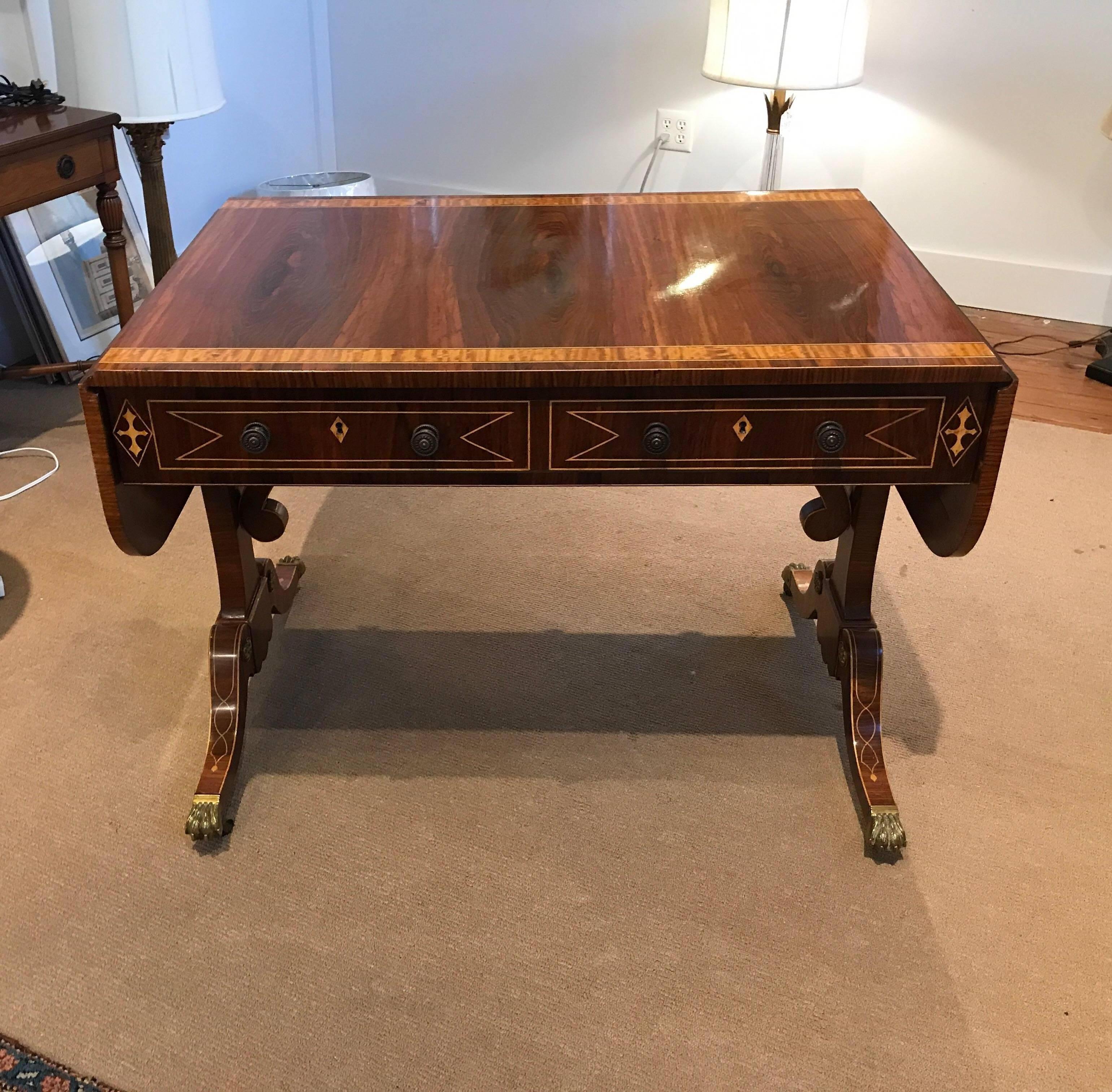 Graceful and elegant rosewood and satinwood inlaid drop leaf console desk. Extraordinary craftsmanship and cabinet maker made in the English Regency style. The figured wood grain with satinwood banding on the top and intertwining pencil inlay on the