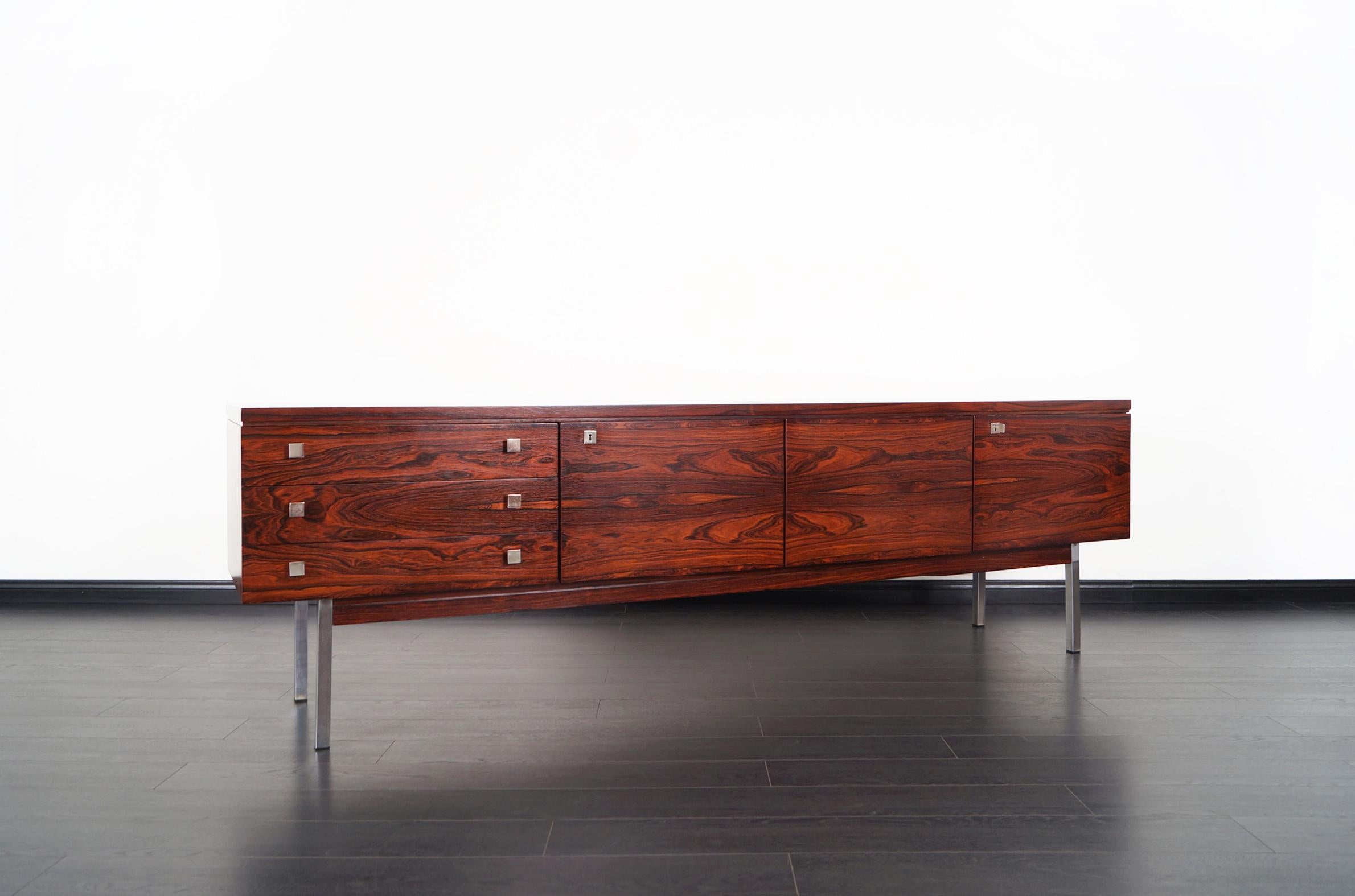 Exceptional rosewood credenza attributed to Dieter Waeckerline, Germany. Phenomenal Brazilian rosewood grain with elegant design. Features three pull out drawers with original handles and three doors that reveal a large shelf and ample storage.