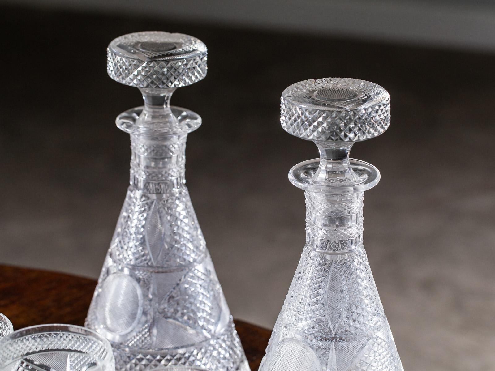 A set of exceptional antique Irish Georgian style cut crystal decanters and glasses circa 1875. Featuring two decanters with stoppers and an assortment of red wine, white wine, water and liqueur glasses this set is notable for the square bases of