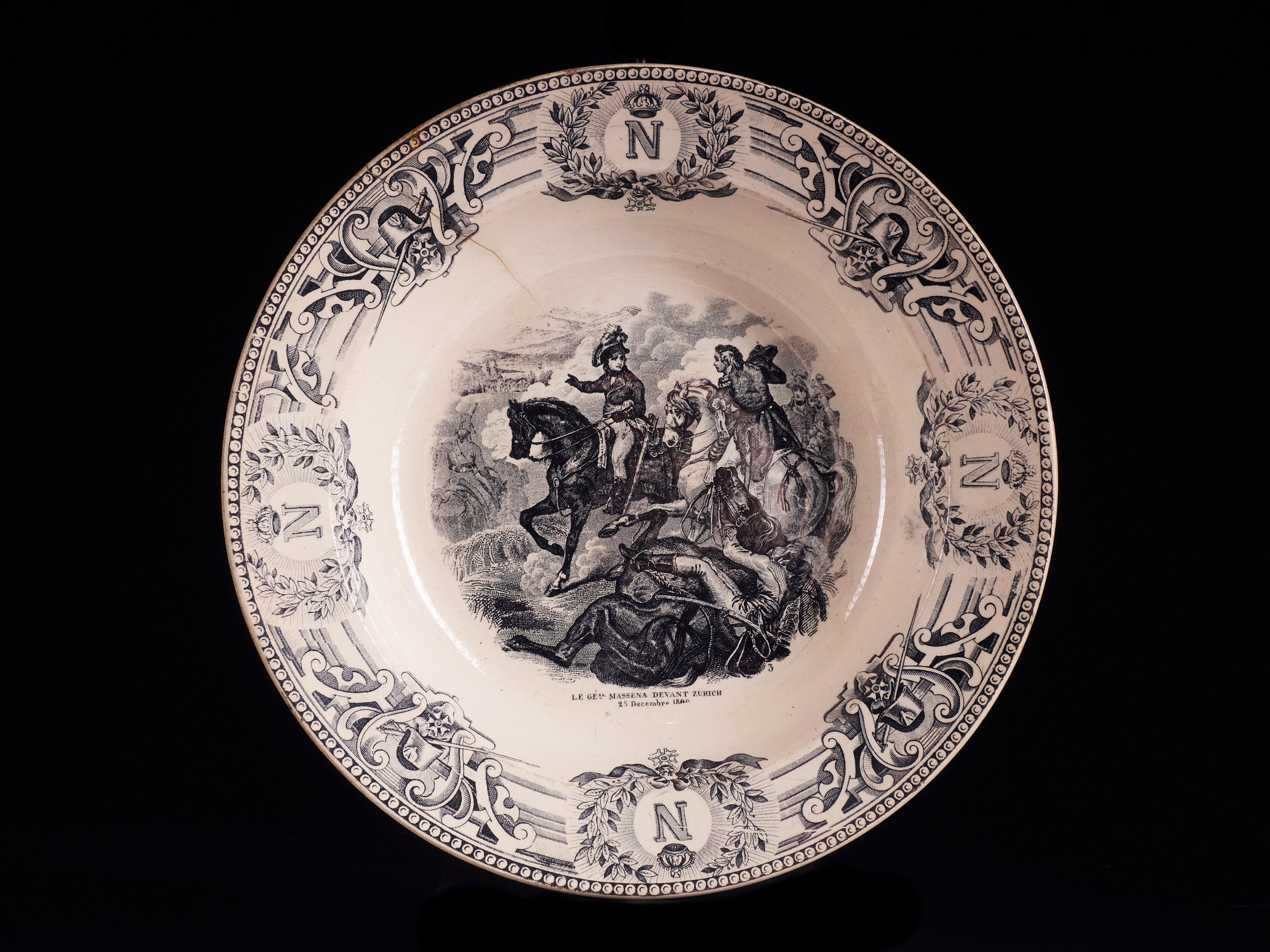 Superbly elegant set of 9 white faïencerie plates from the 1890s depicting major French battle scenes of the late 18th and early 19th century. The items are beautifully painted with stamped black designs based on a 