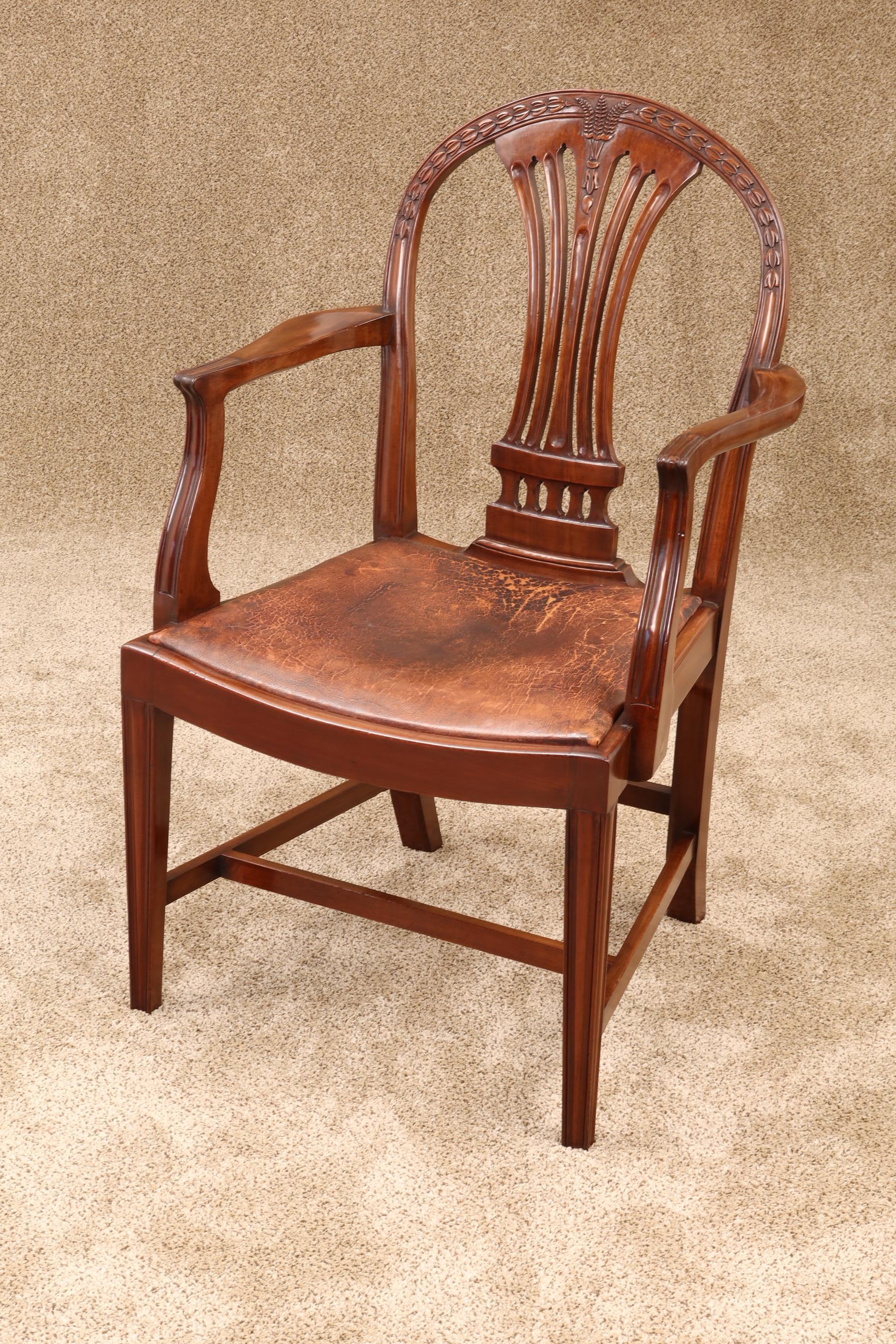 An exceptional set of English Hepplewhite style dining chairs. Many things set these chairs apart from others. The mahogany is particularly dense and heavy and takes the carved detail very well. The hooped backs are carved with wheat and bell