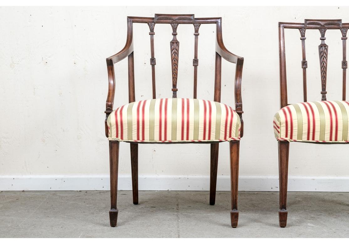 Set of 8 Federal style mahogany dining chairs comprised of 2 armchairs and 6 side chairs with upholstered seats  with web construction. The chairs with backrests displaying foliate, floral and feathered carvings, resting on tapering spear front feet