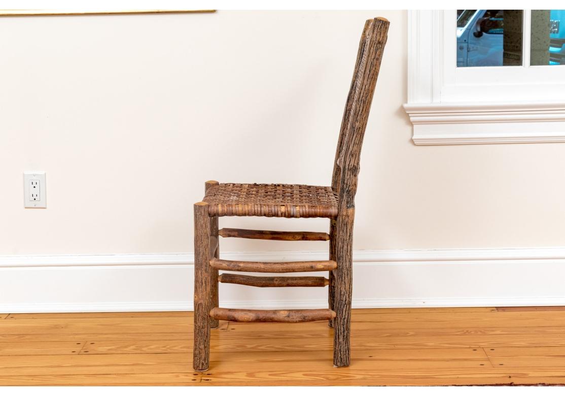 Un conjunto muy bien elaborado de 10 sillas de comedor estilo Adirondack fabricadas con secciones de ramas macizas decapadas y torneadas y gruesos asientos y respaldos de caña estirada a mano. El conjunto con buena comodidad , peso y solidez.