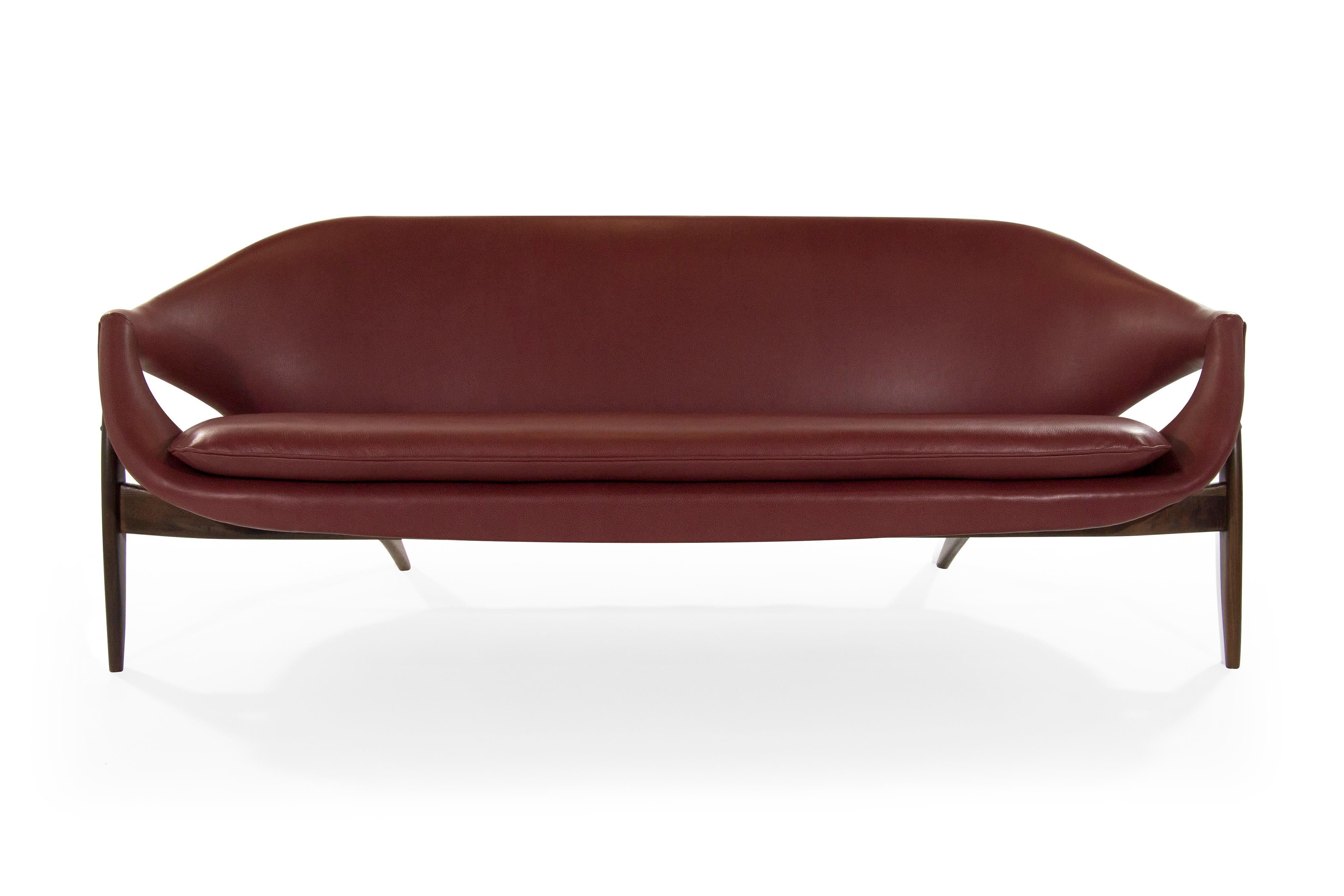 Rare sofa designed by Italy born furniture designer Luigi Tiengo and produced by the Canadian manufacturer Cimon in 1963. Sculptural shape featuring a fully restored walnut base, newly upholstered in chianti leather. Striking from all angles.