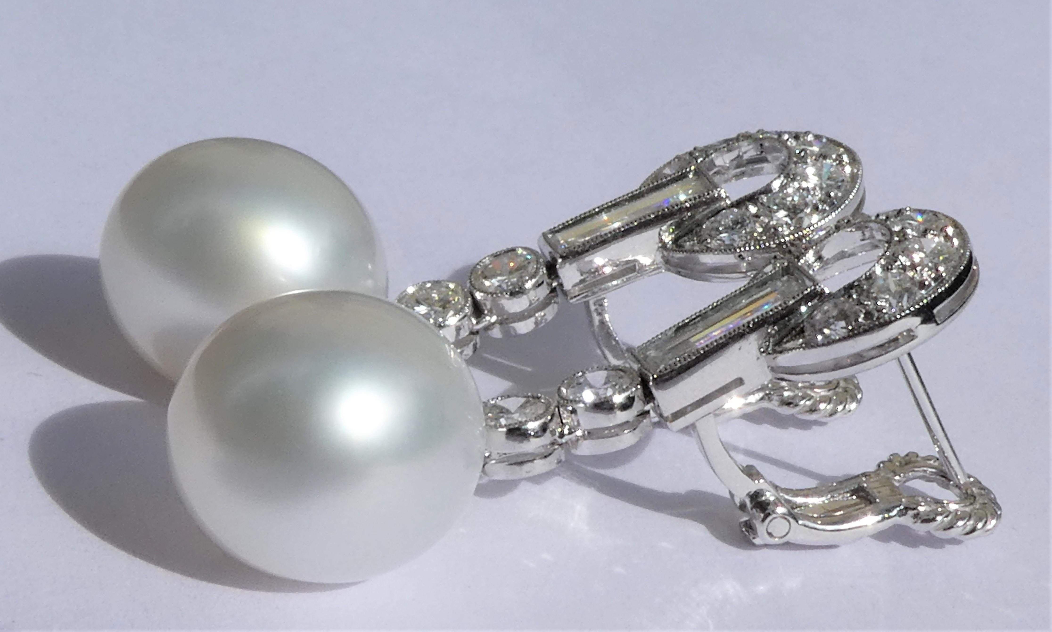 A pair of white immaculate lustrous slightly oval South Sea cultured pearls measuring 1.9 x 1.2 cm - 0.75 x 0.47 inch dangle elegantly from these movable drop earrings. They are handcrafted in 18 karat white gold and one-of-a-kind. The diamonds of