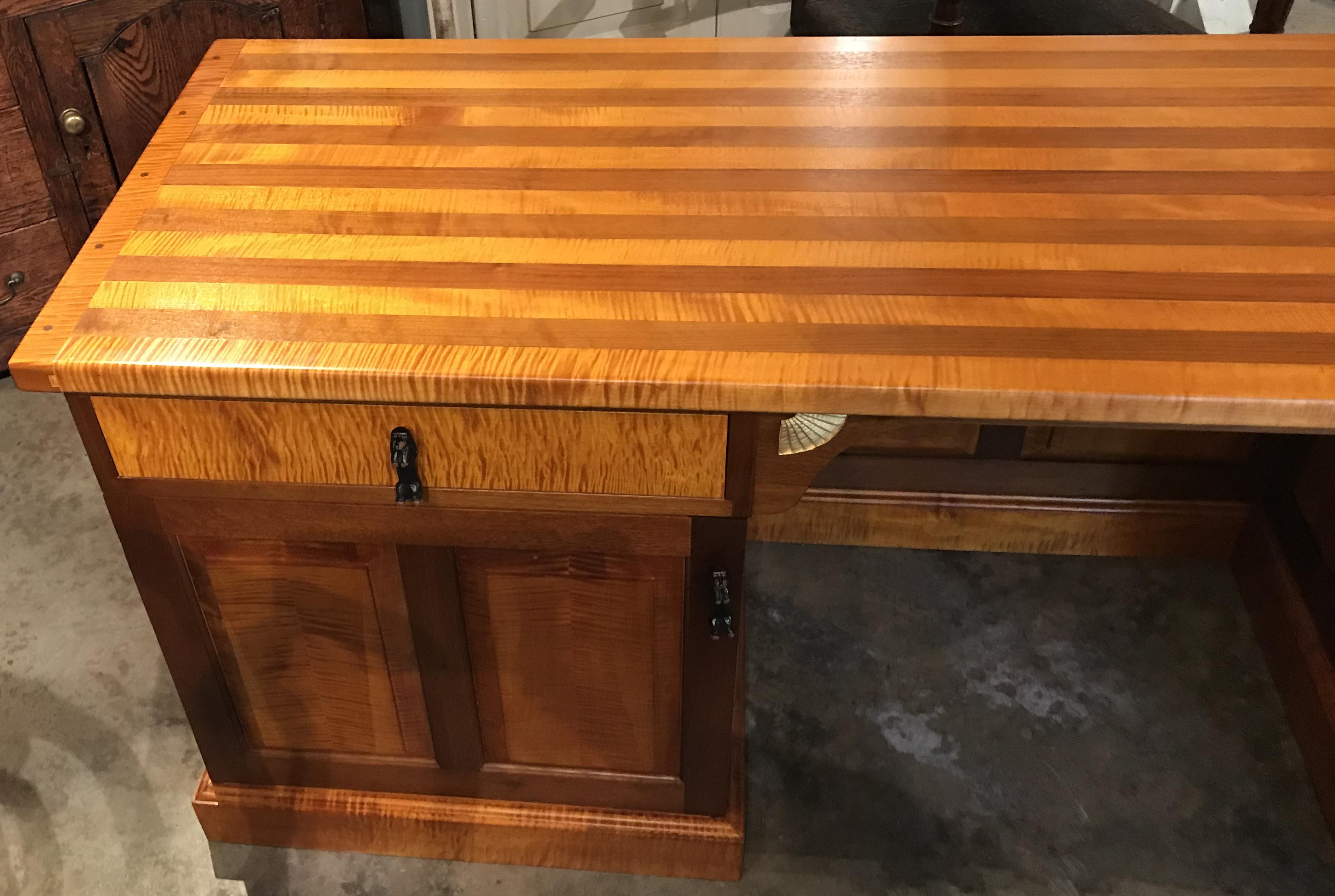 An exceptional custom contemporary desk in tiger maple and walnut designed by Stephen Huneck of St. Johnsbury, VT, with rectangular two tone top in figured maple and walnut with breadboard ends and pegged construction, surmounting a center kneehole