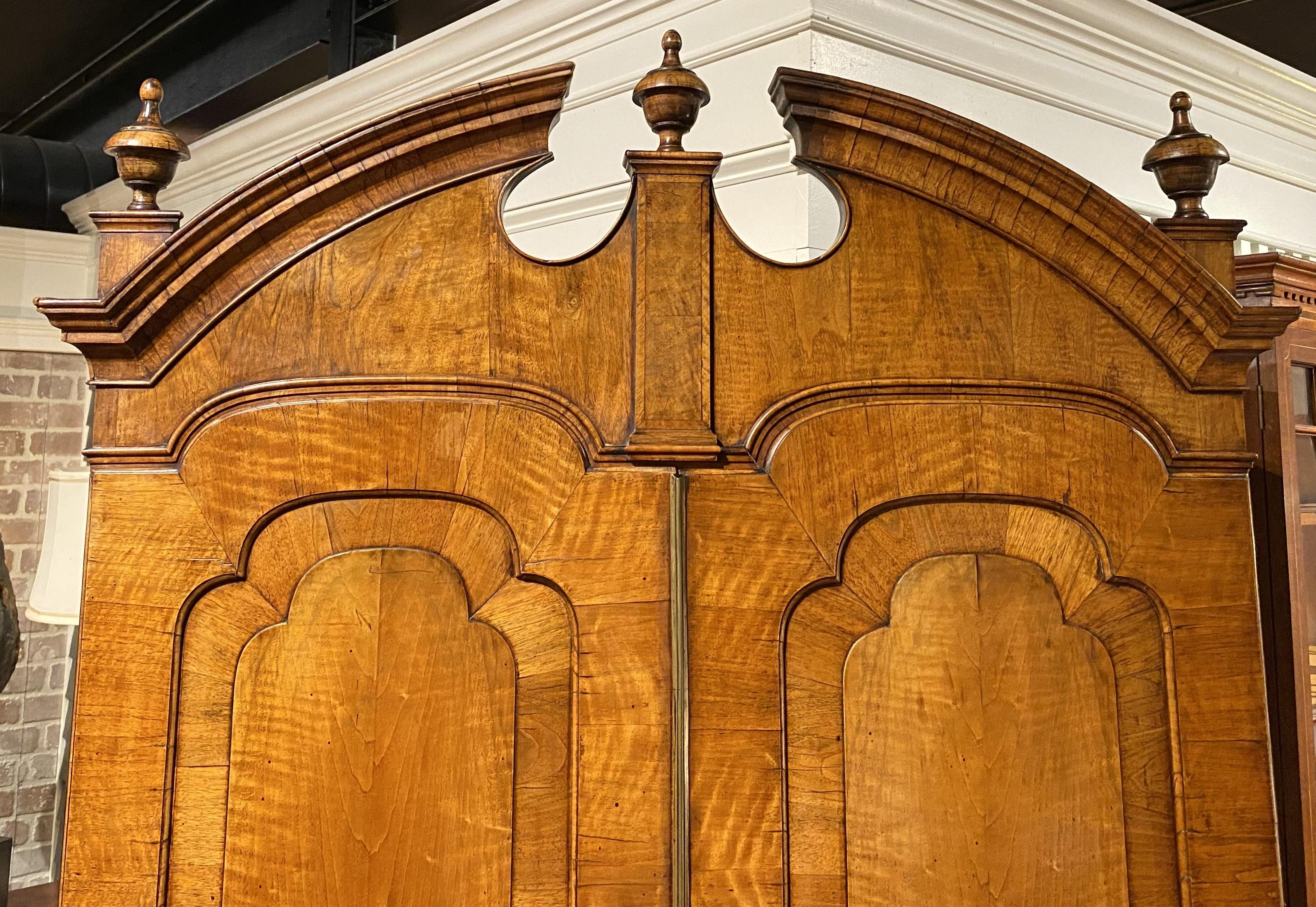 Excepcional ejemplo de escritorio de secretaria inglés de finales de la dinastía Jorge I, en nogal, cuya parte superior tiene un frontón de arco roto moldeado con remates en forma de urna sobre dos puertas arqueadas con paneles, que se abren a dos