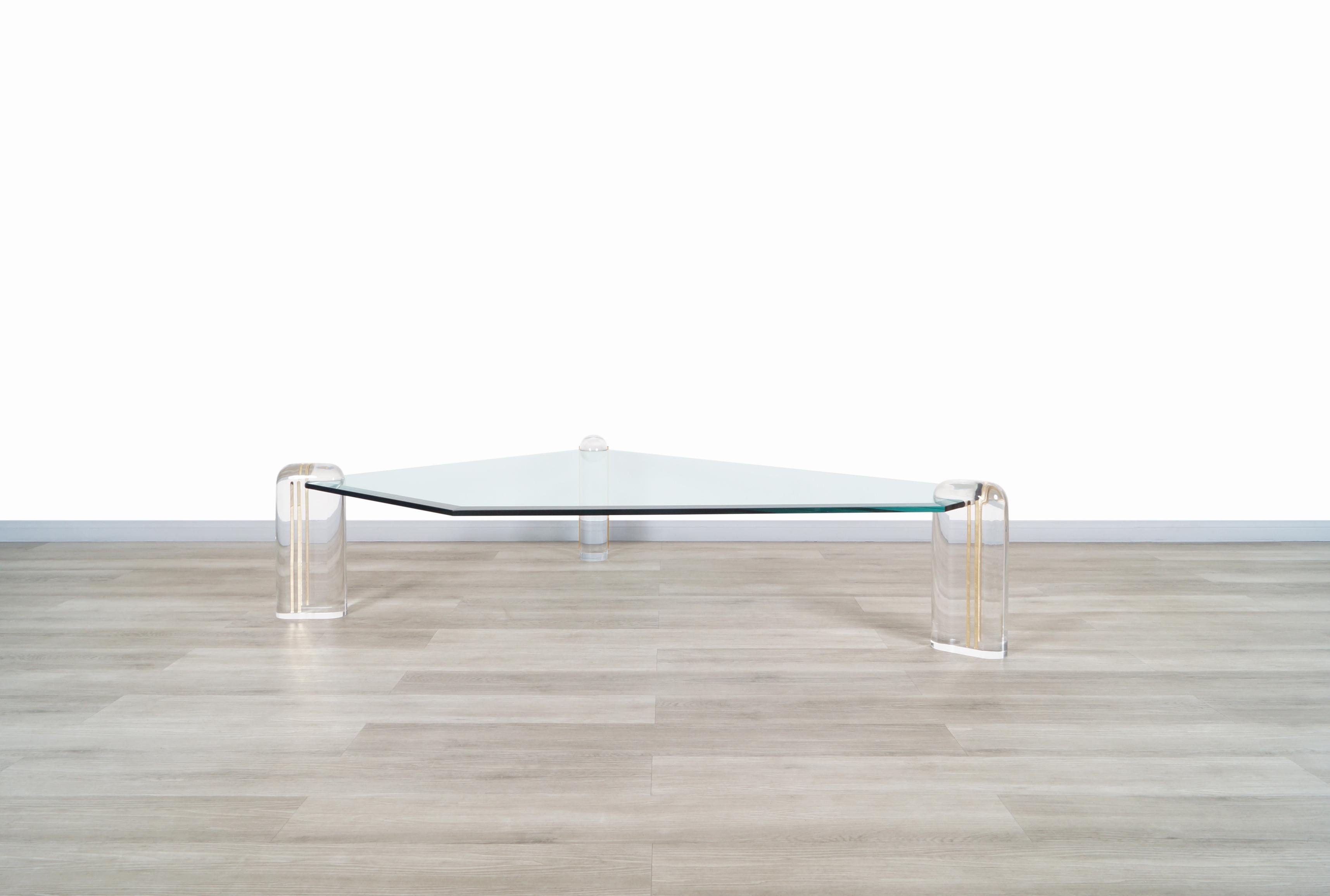 Exceptional vintage lucite and glass coffee table designed by Karl Springer in the United States, circa 1980s. This coffee table has a unique design in which its construction materials and the shape of its design Stand out. It features a large