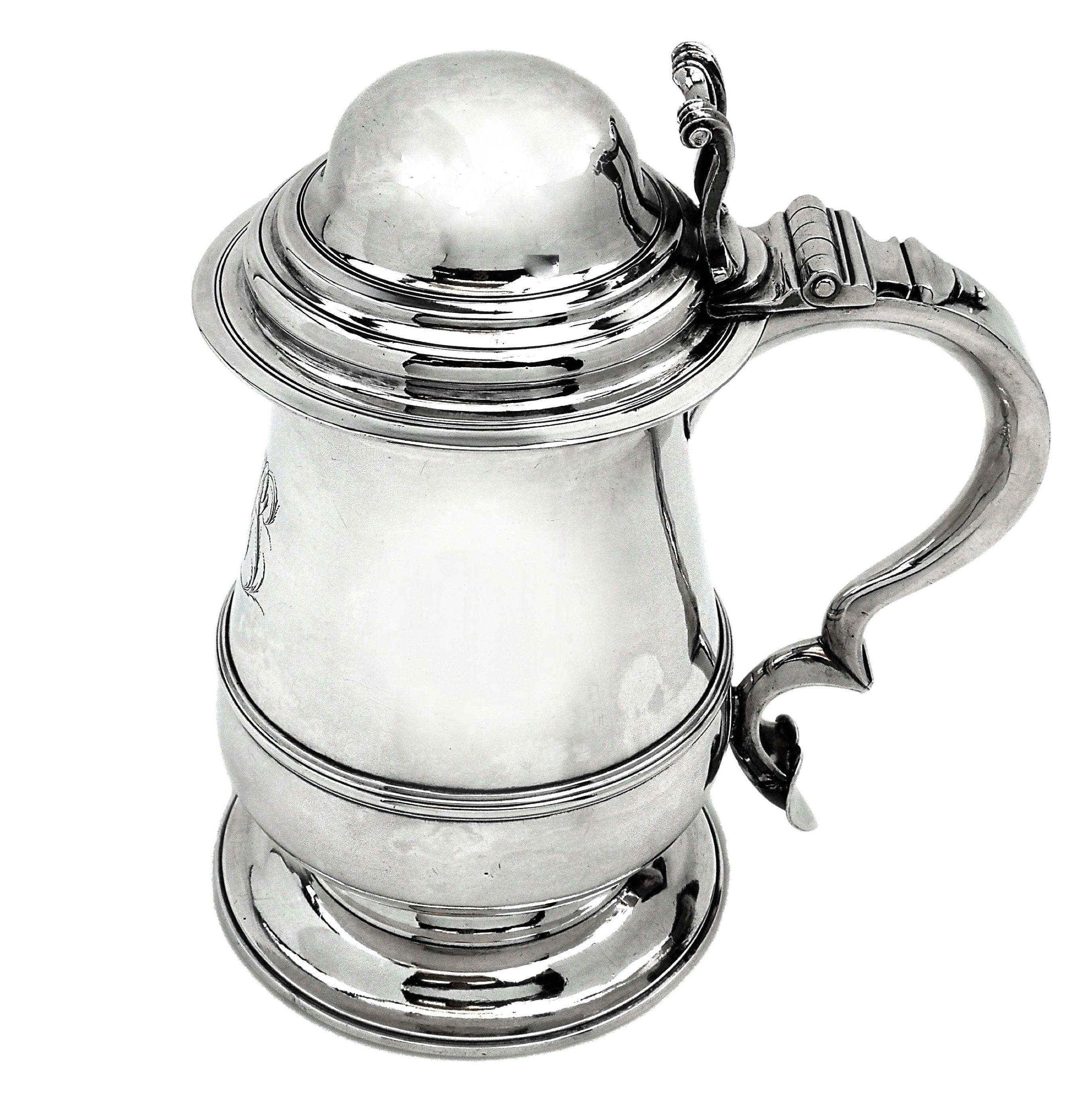 A magnificent Antique George III solid silver lidded tankard. This Tankard has a traditional Georgian baluster shaped body on a wide spread foot topped with a substantial domed hinged lid with an impressive thumb piece. This Tankard features all the