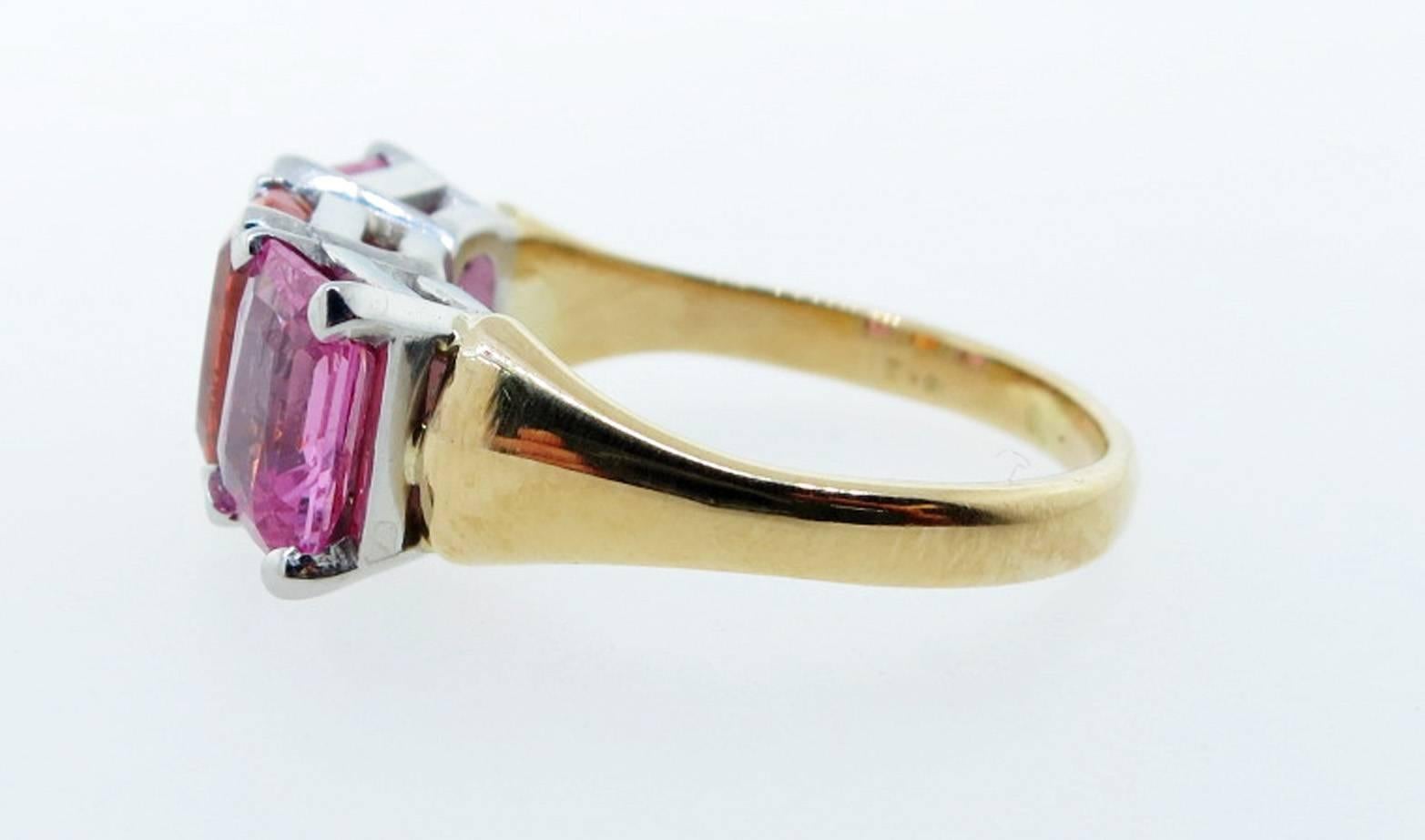 Scintillating 18kt. yellow and white gold natural pink sapphire and Mandarin garnet ring. The center is prong set in white gold with an oval faceted natural garnet measuring approx 8.4 mm. x 6.6 mm. weighing approx 2.3cts. Each side is set with a