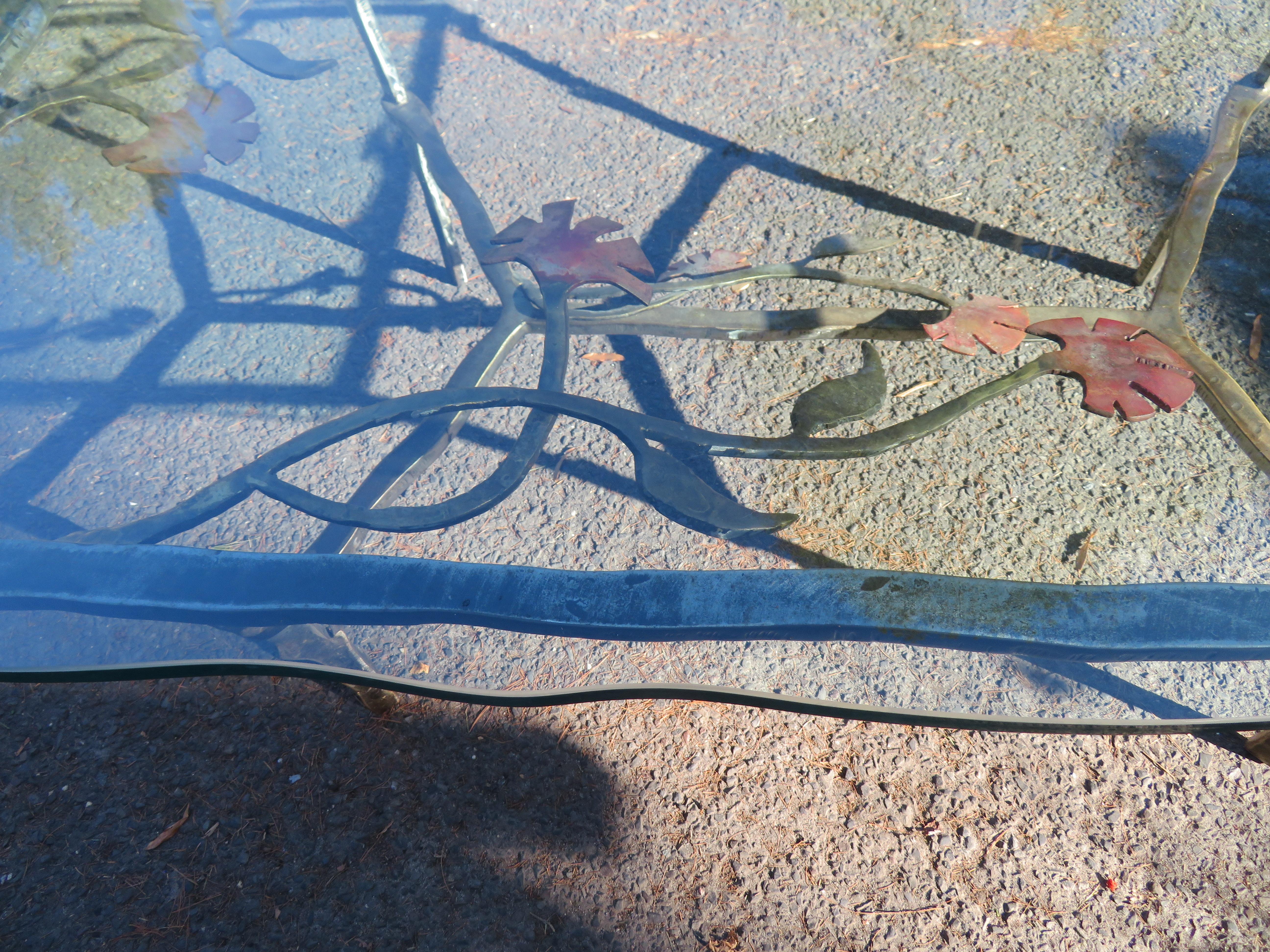 Exciting artisan dining table with hand-welded steel and bronze base with thick floating glass top by Silas Seandel, American 1970s (signed “Silas Seandel” on the top corner). This table is very unique with thick hand-forged steel legs shaped into