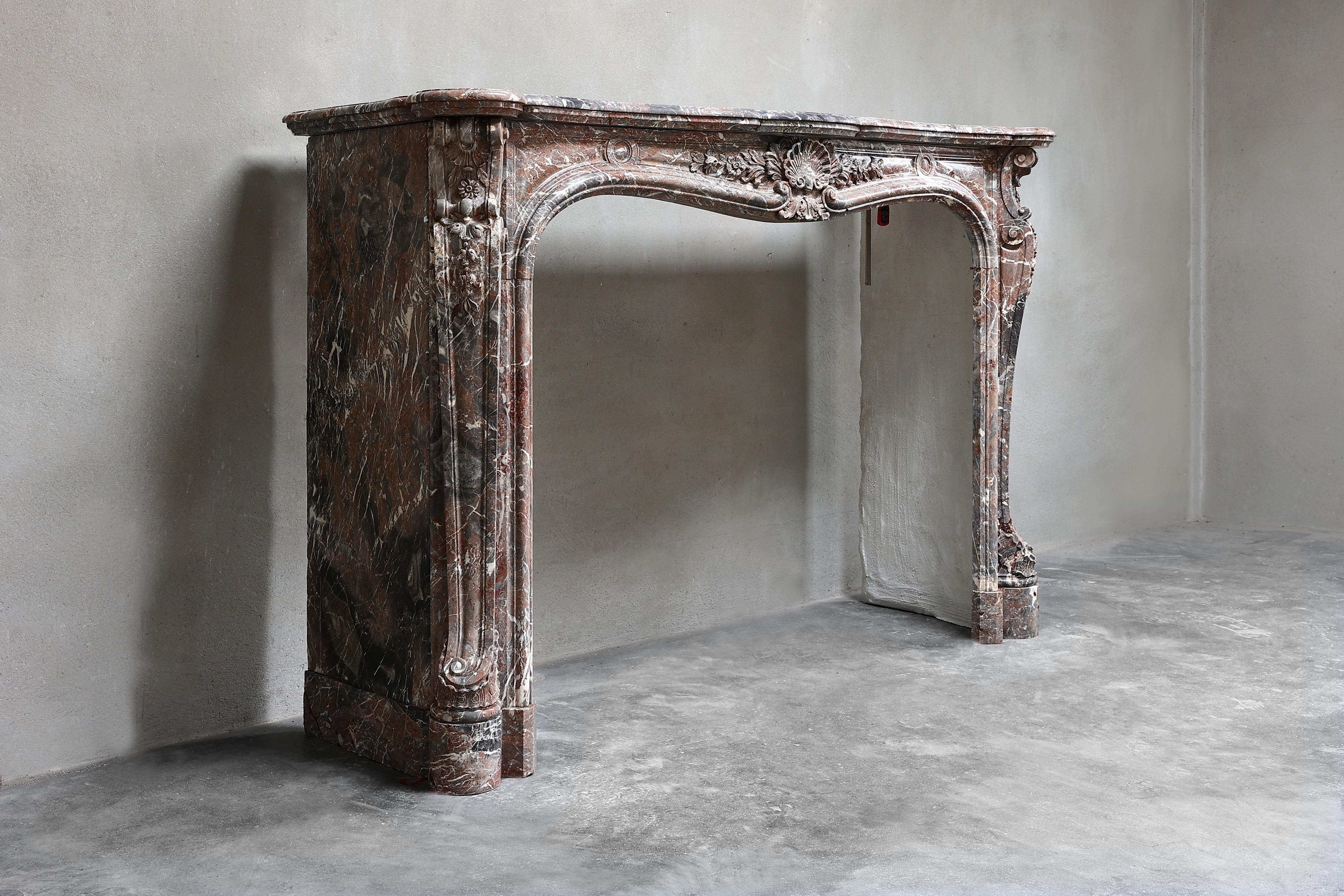 Très belle et exclusive cheminée ancienne en marbre de Saint Remy de Belgique. Ce type de marbre a une nuance de couleur chaude et les beaux ornements ciselés donnent à cette cheminée un aspect chic. La cheminée date de la fin du 19ème siècle et est