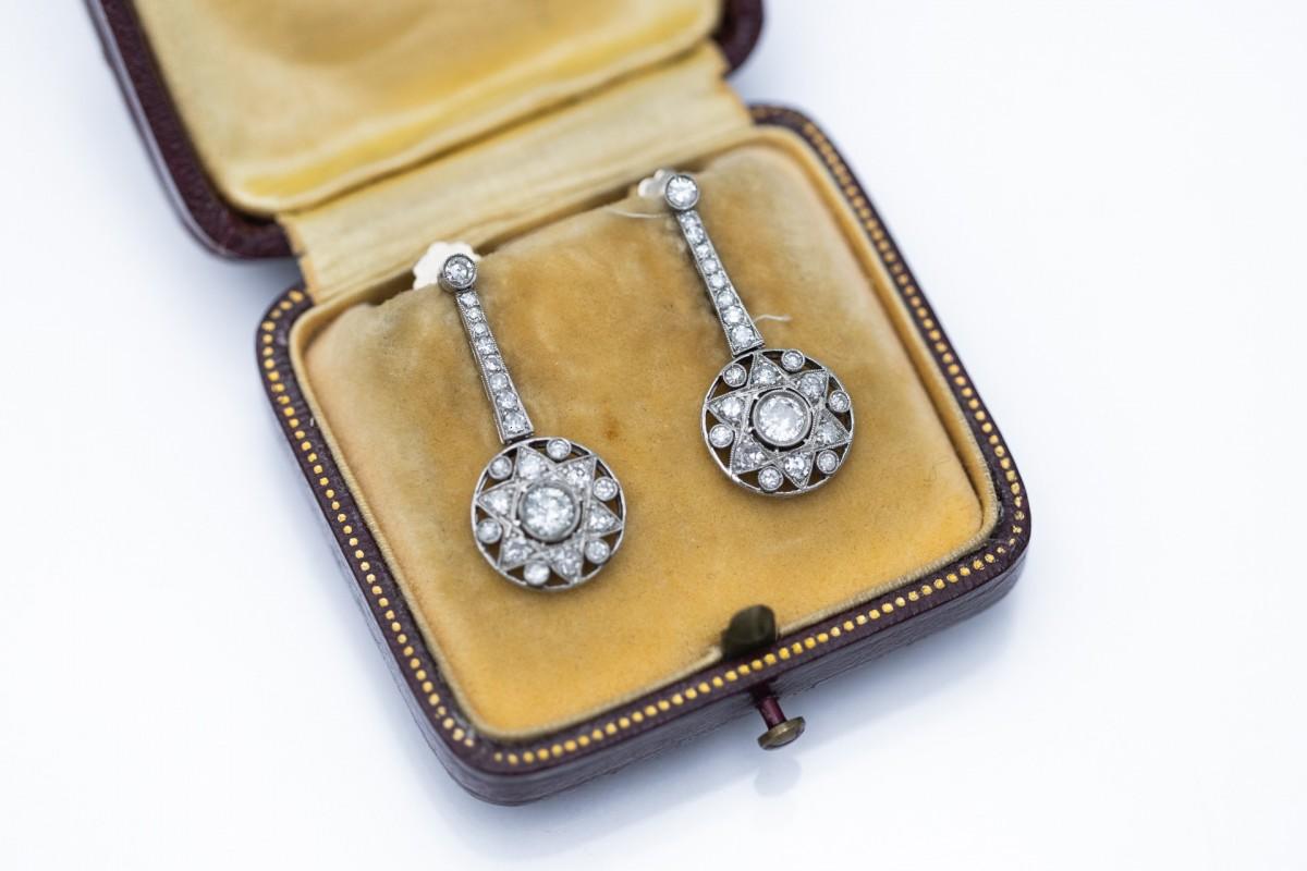Boucles d'oreilles exclusives de style Art déco ancien en or jaune 18 carats et platine avec un motif étoilé.

Boucles d'oreilles pendantes serties de 2 diamants centraux pesant environ 0,34ct et de 48 diamants en taille 8/8 pesant environ 0,70ct