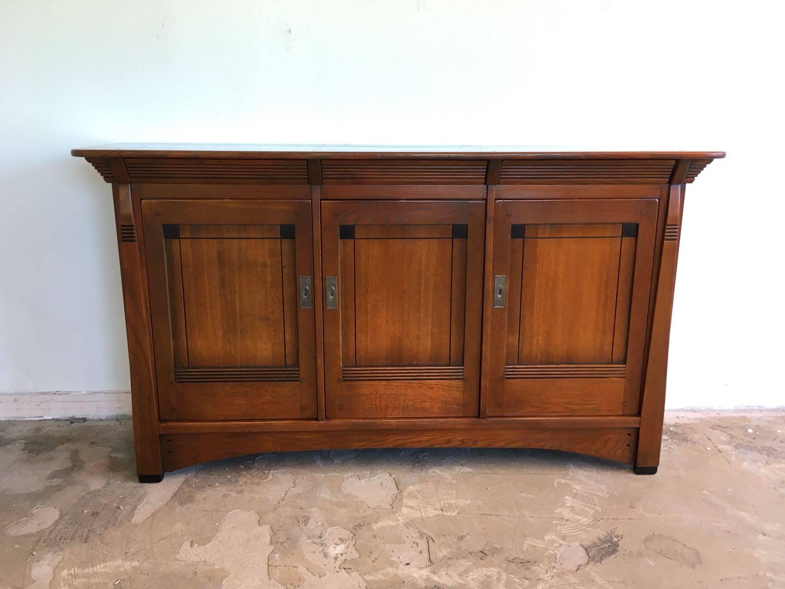 This high quality sideboard made of French oak was designed and manufactured by (Frits) Schuitema & Zonen in The Netherlands. It features three doors and within two, in height adjustable, shelves. This piece also features three hidden drawers. This