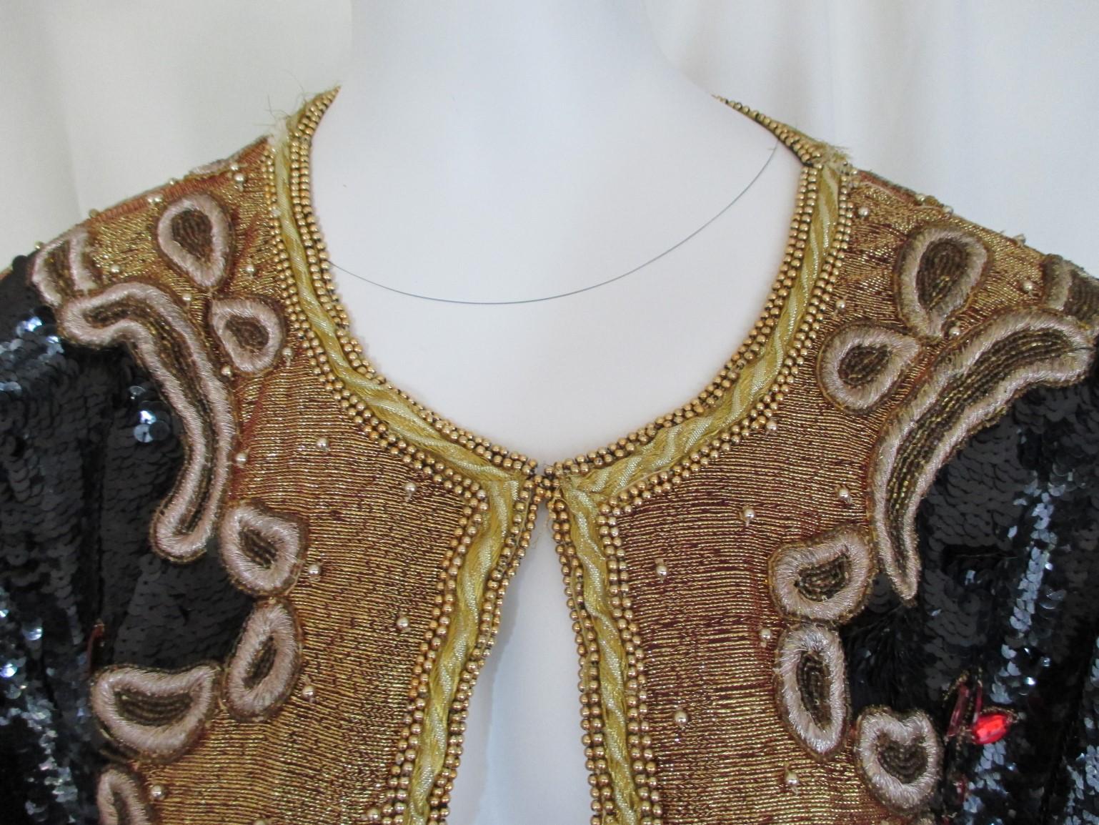 This exclusive vintage evening jacket with 6 front closing hooks, is embroided with red stones, black sequins, gold embroidered and has shoulder pads.
Its in fair pre-owned condition with some wear at the collar and stones.
Appears to be