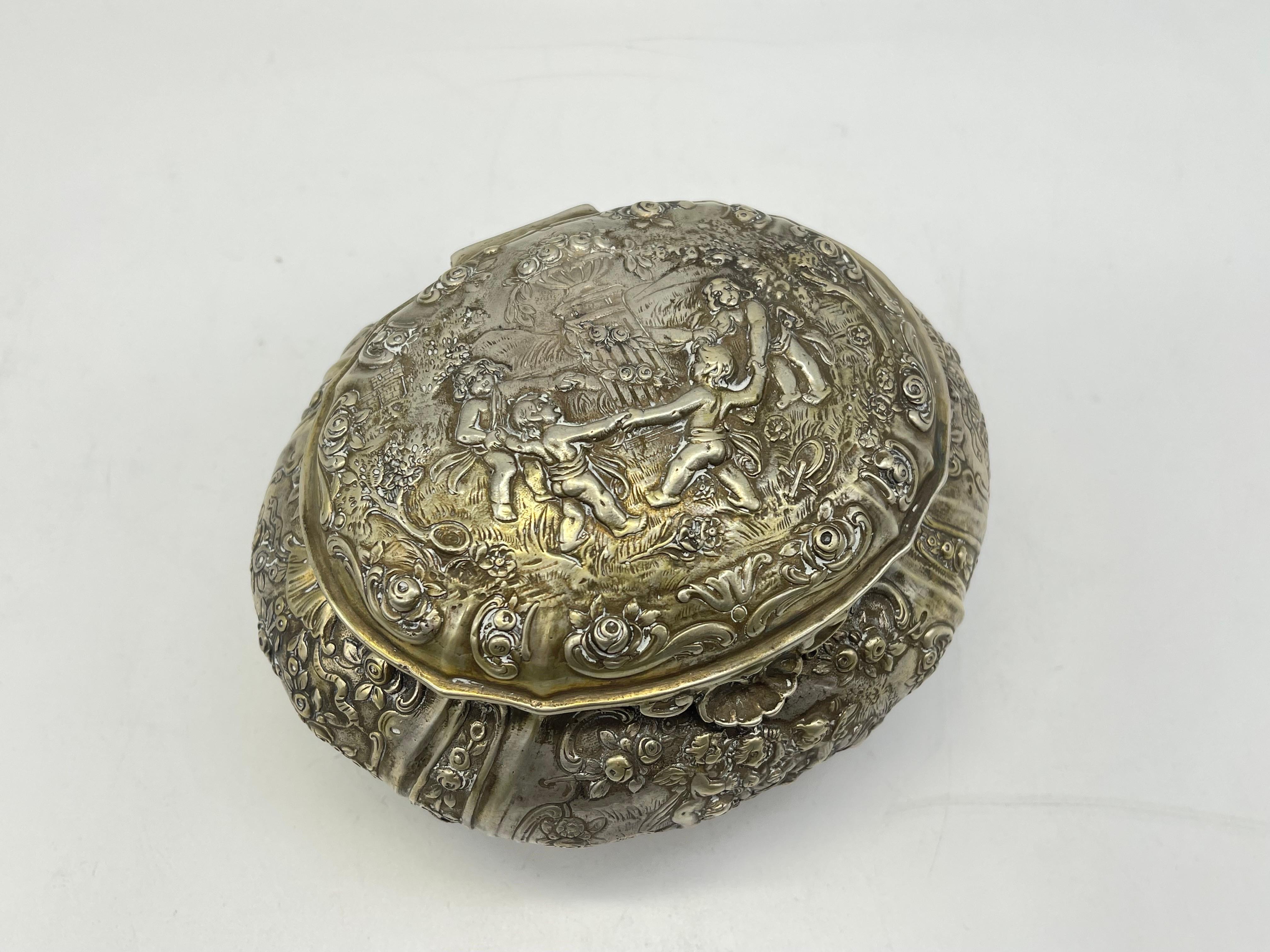 Antique 800 Silver Bonboniere / Sugar- Lidded box

Half moon & crown - Germany - 800 Silver
Flowers, Putto & Children ornament - inside gilded
stand on 4 feet

Weight: 372 grams

The condition can be seen in the pictures.